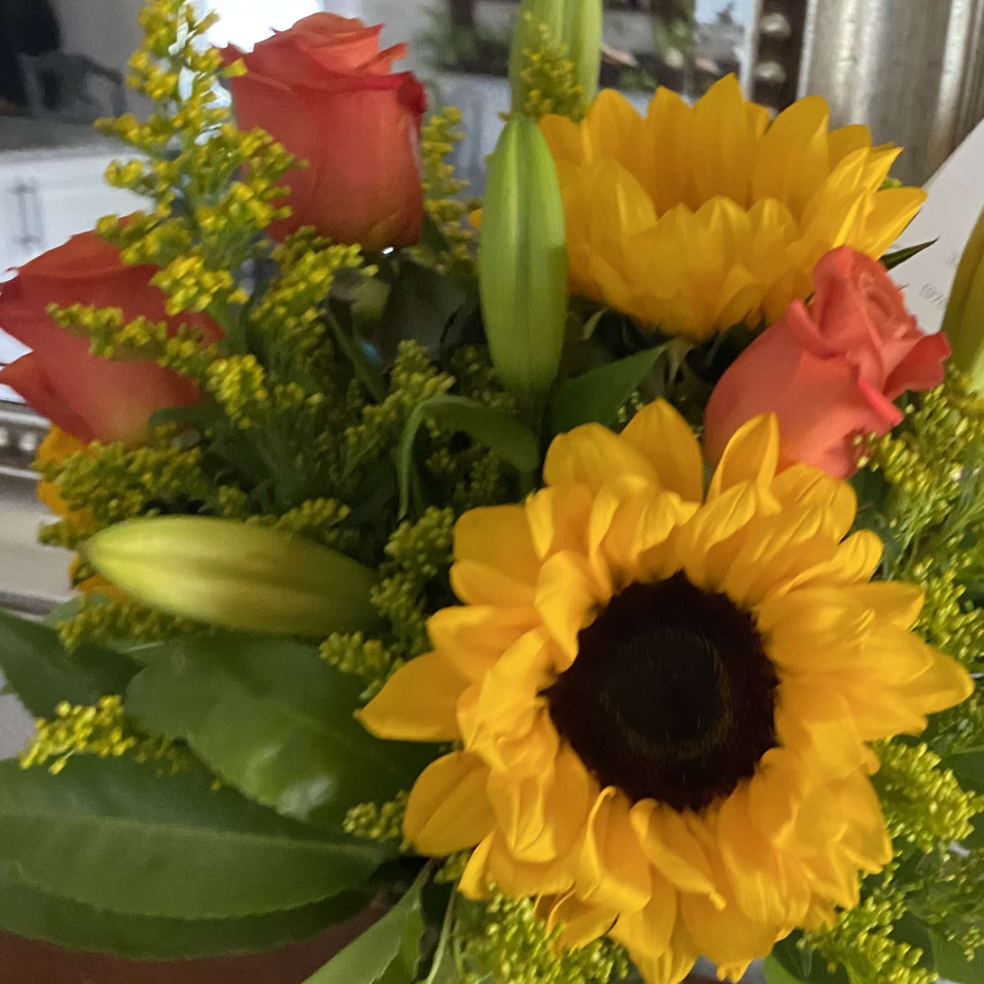 Bouquet with yellow sunflowers, coral roses, and unopened lily buds