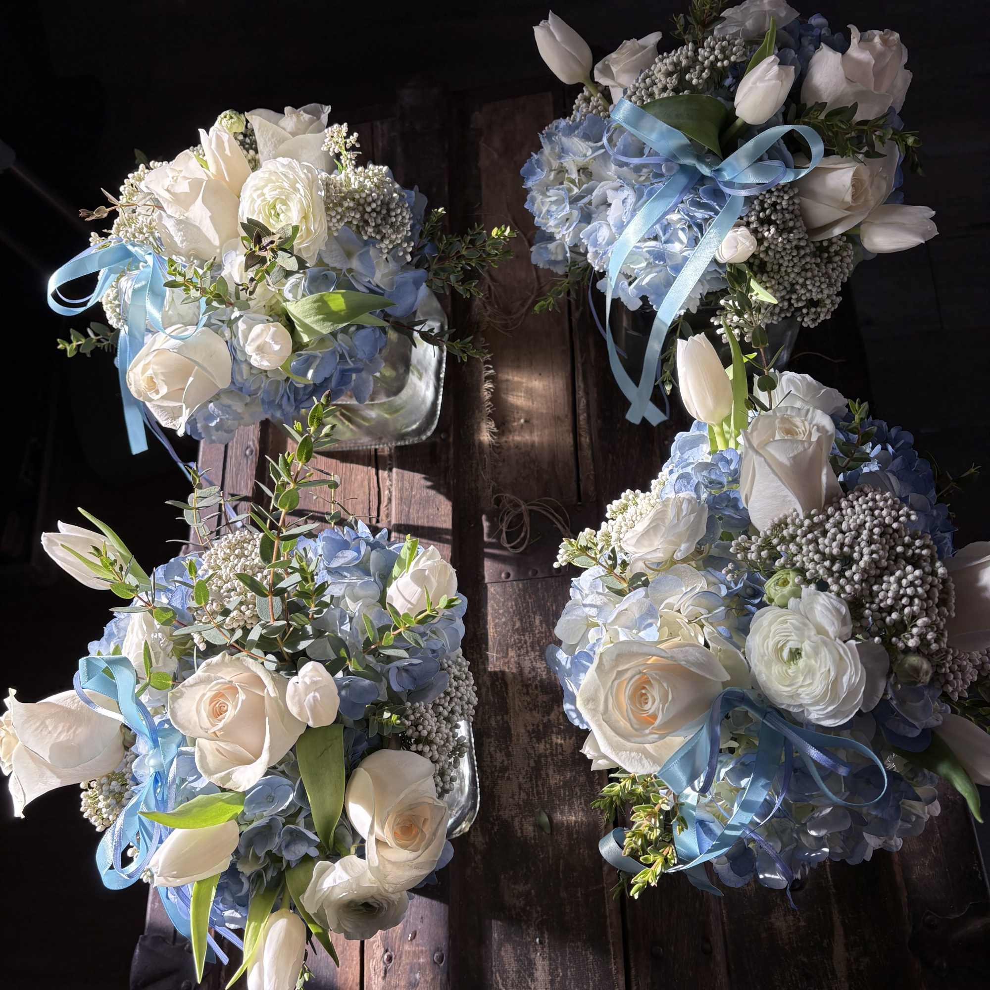 Four blue and white floral bouquets with ribbon on a wooden surface