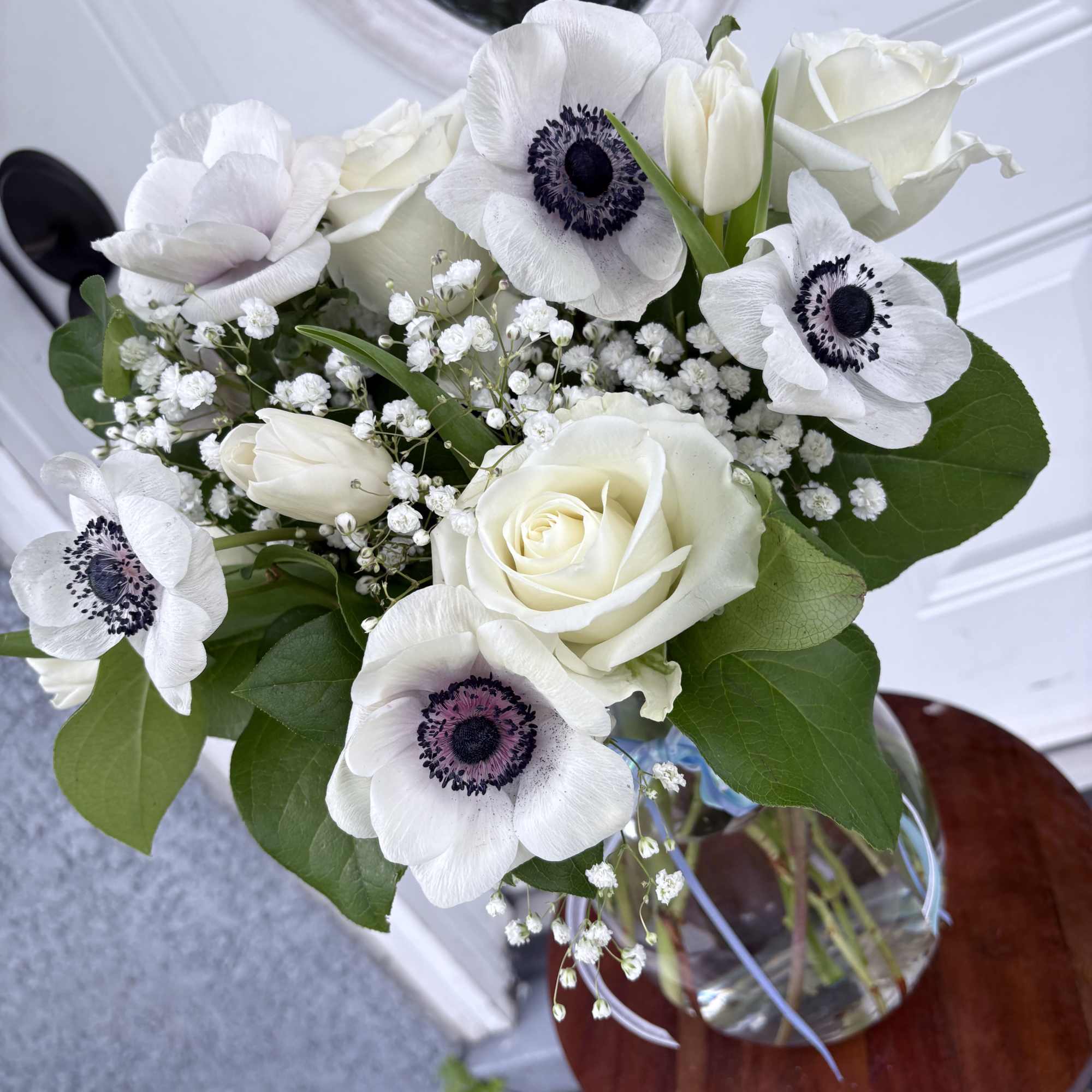 White roses and anemones arranged in a glass vase