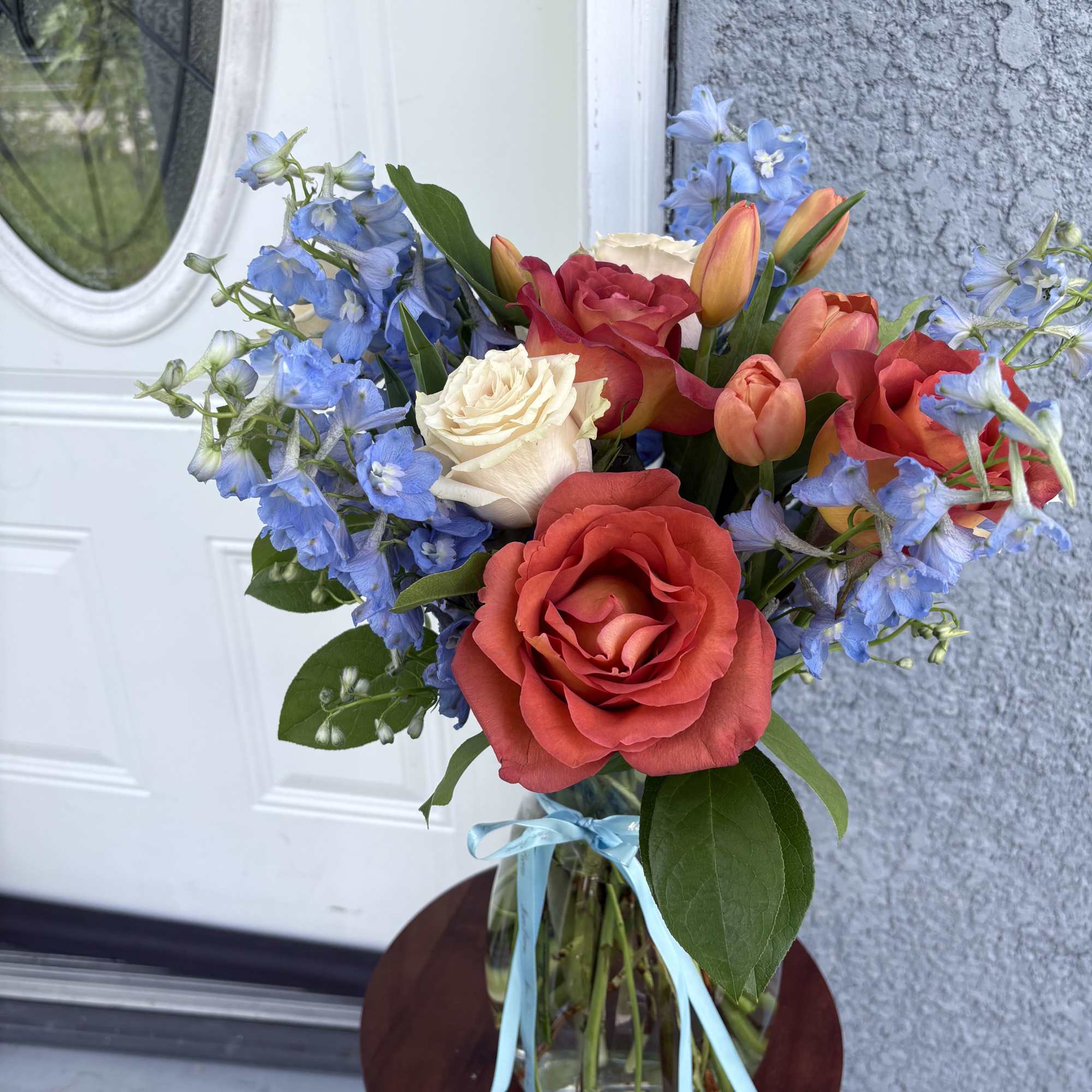 Bouquet of red and cream roses with blue delphinium in a glass vase