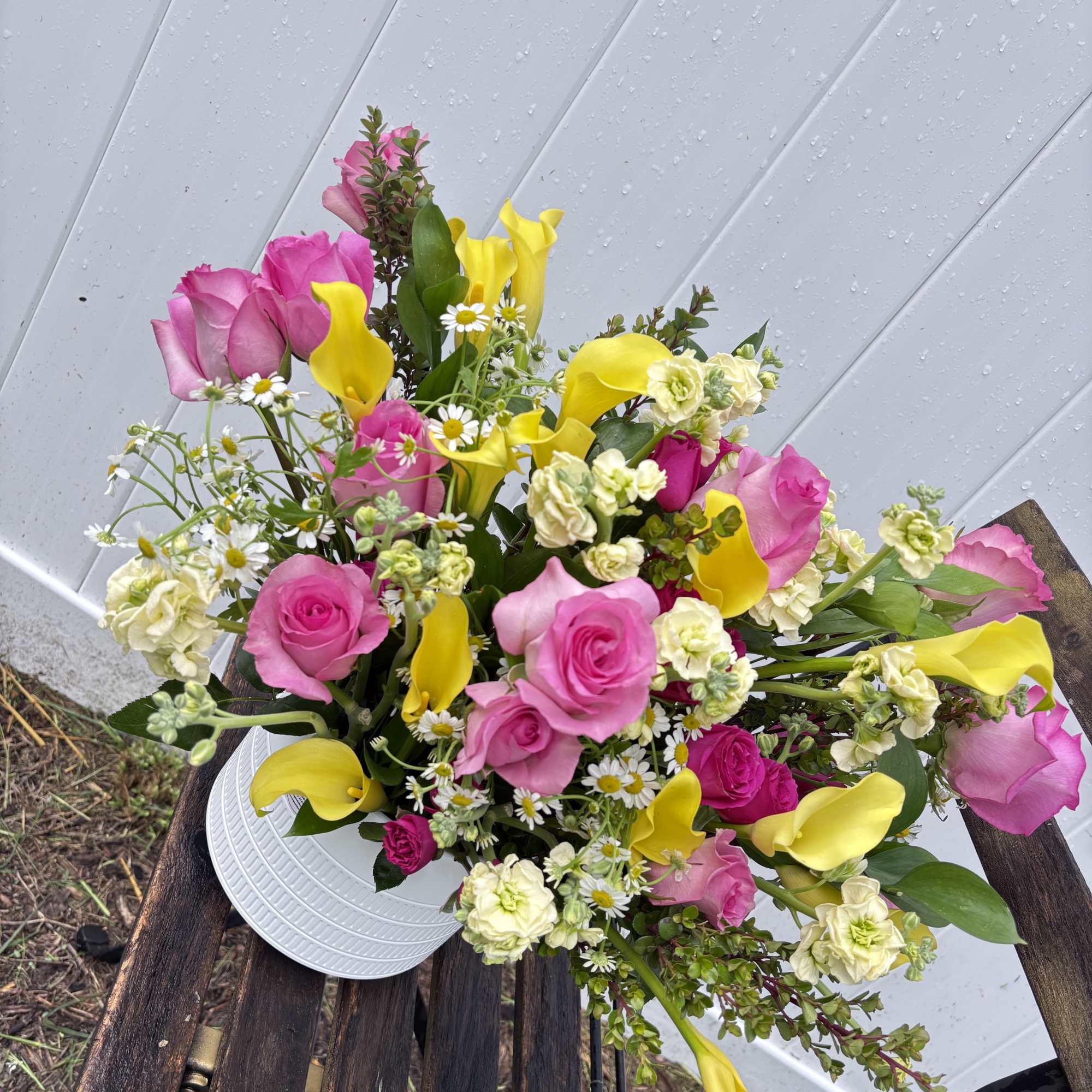 Bouquet of pink roses and yellow calla lilies in a white vase