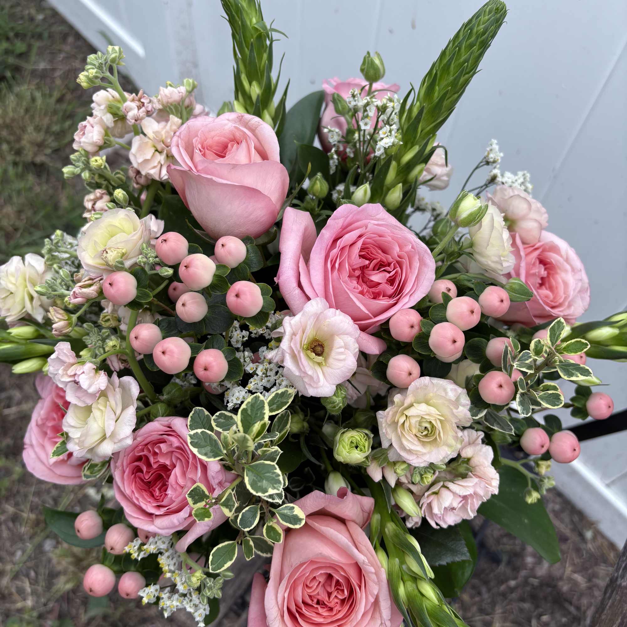 Pink roses and mixed blooms arranged in a hand-tied bouquet