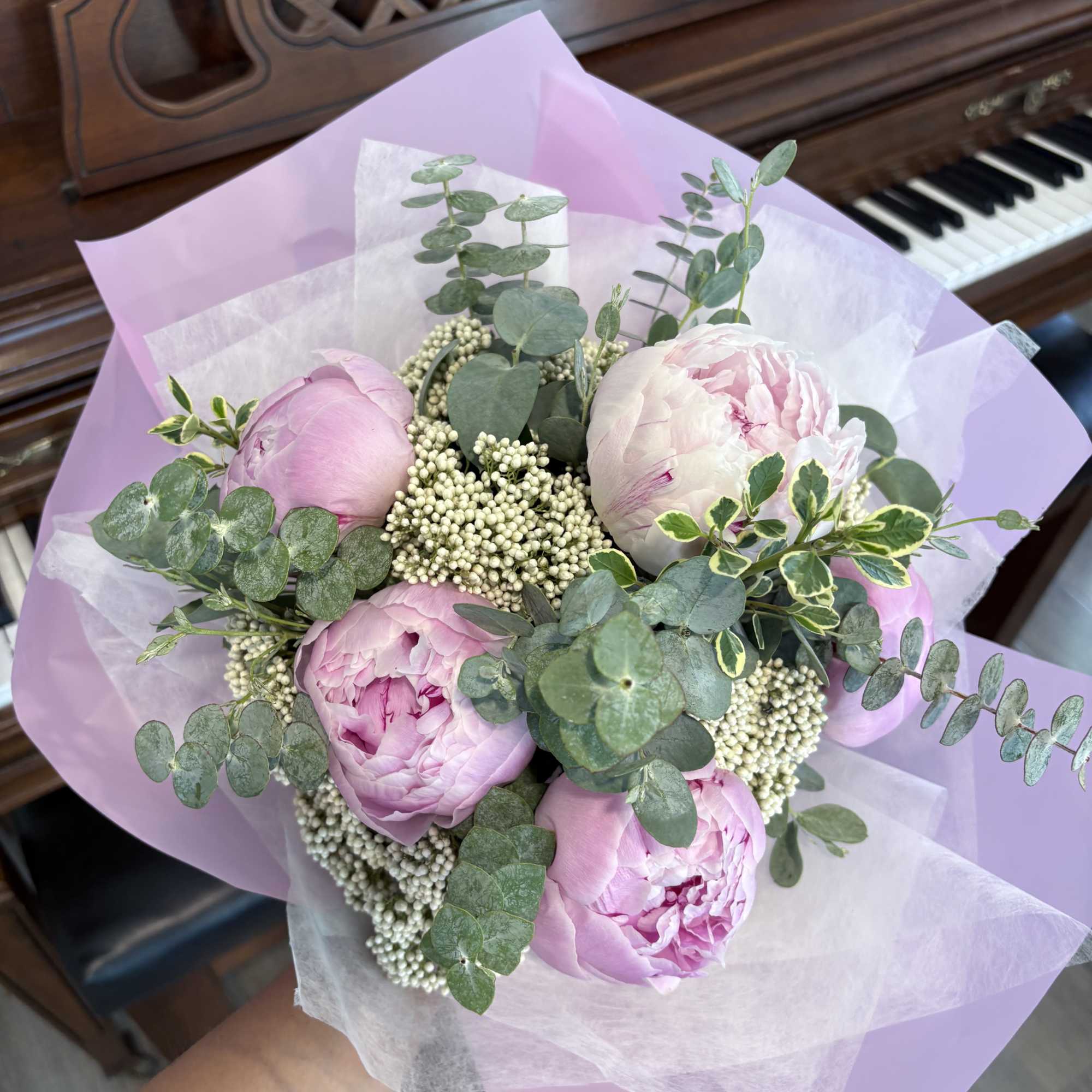 Pink peony bouquet with eucalyptus and white filler wrapped in lavender paper