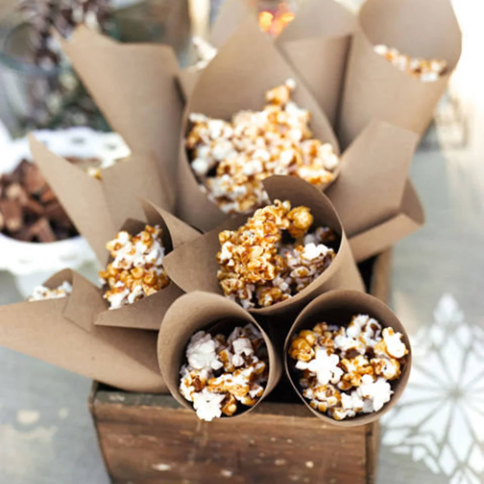 Paper cones of caramel popcorn arranged in a wooden crate