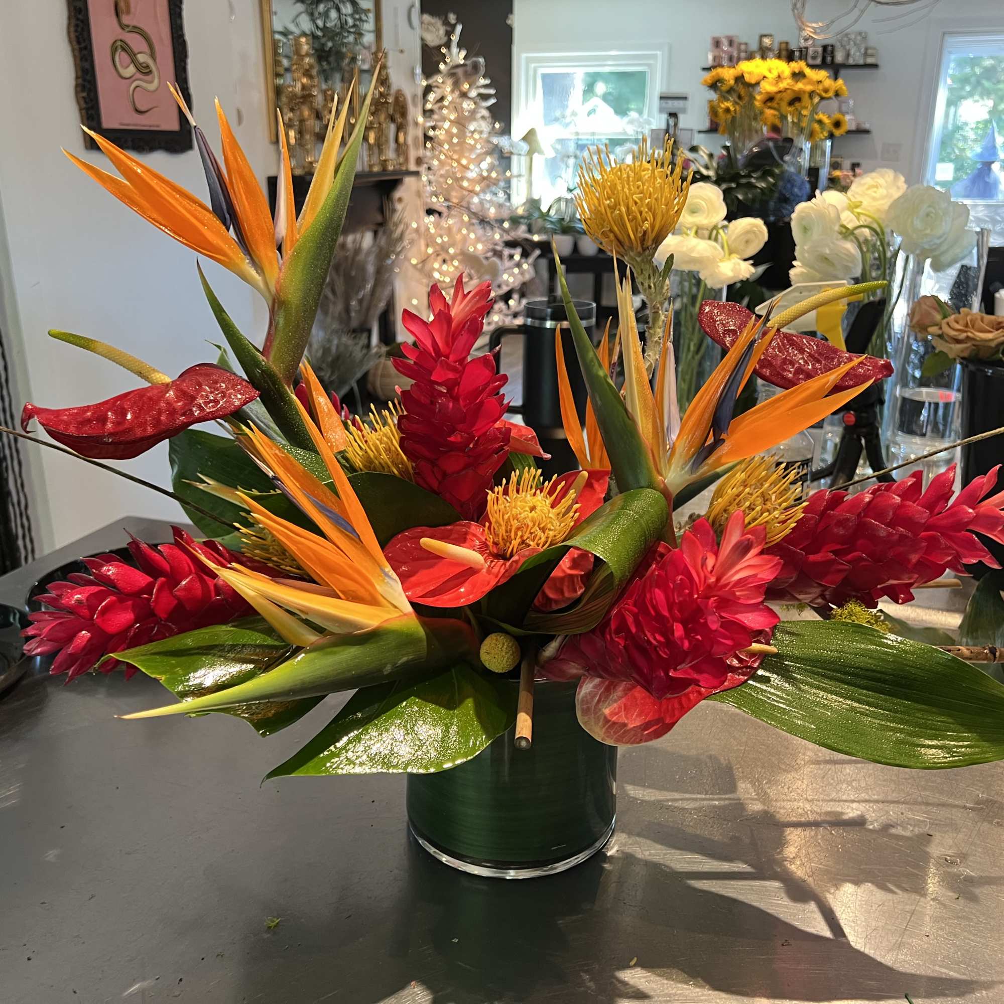 Tropical bouquet with orange bird-of-paradise and red flowers in a glass vase
