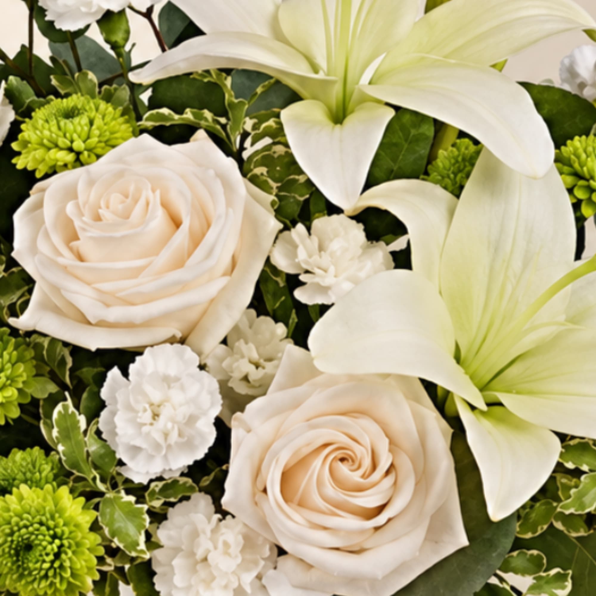 Cream roses and white lilies with green chrysanthemums in a floral arrangement