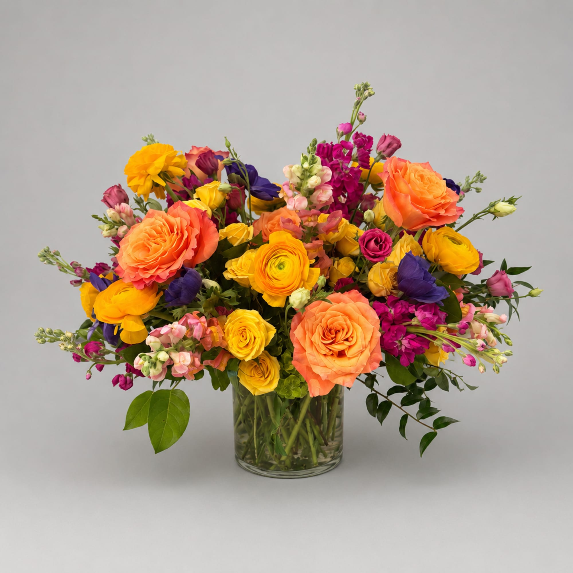 Colorful bouquet of roses and mixed blooms in a clear glass vase