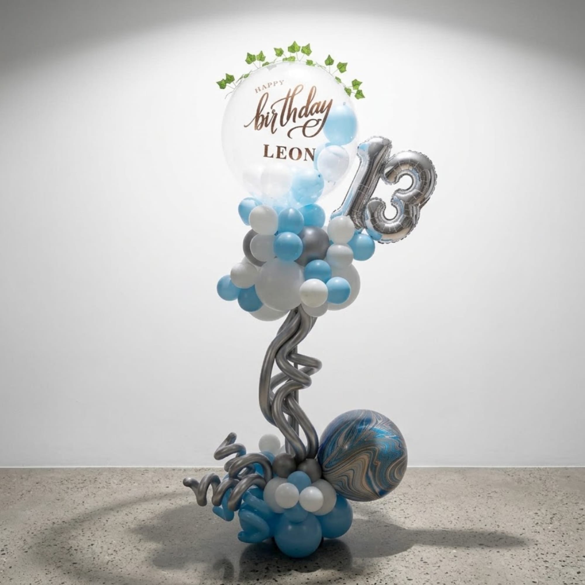 Birthday balloon arrangement with blue, white, and silver balloons and a large "13"