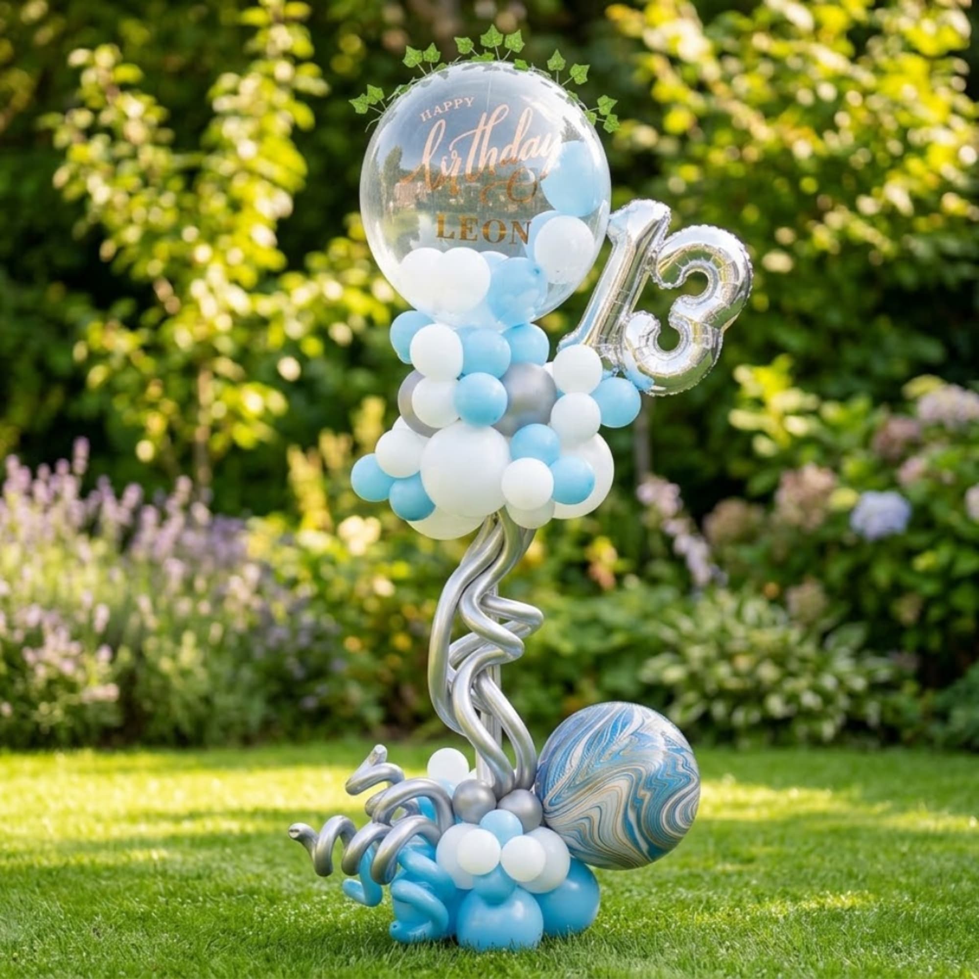 Birthday balloon display with a large clear balloon, silver "13," and blue-white balloons