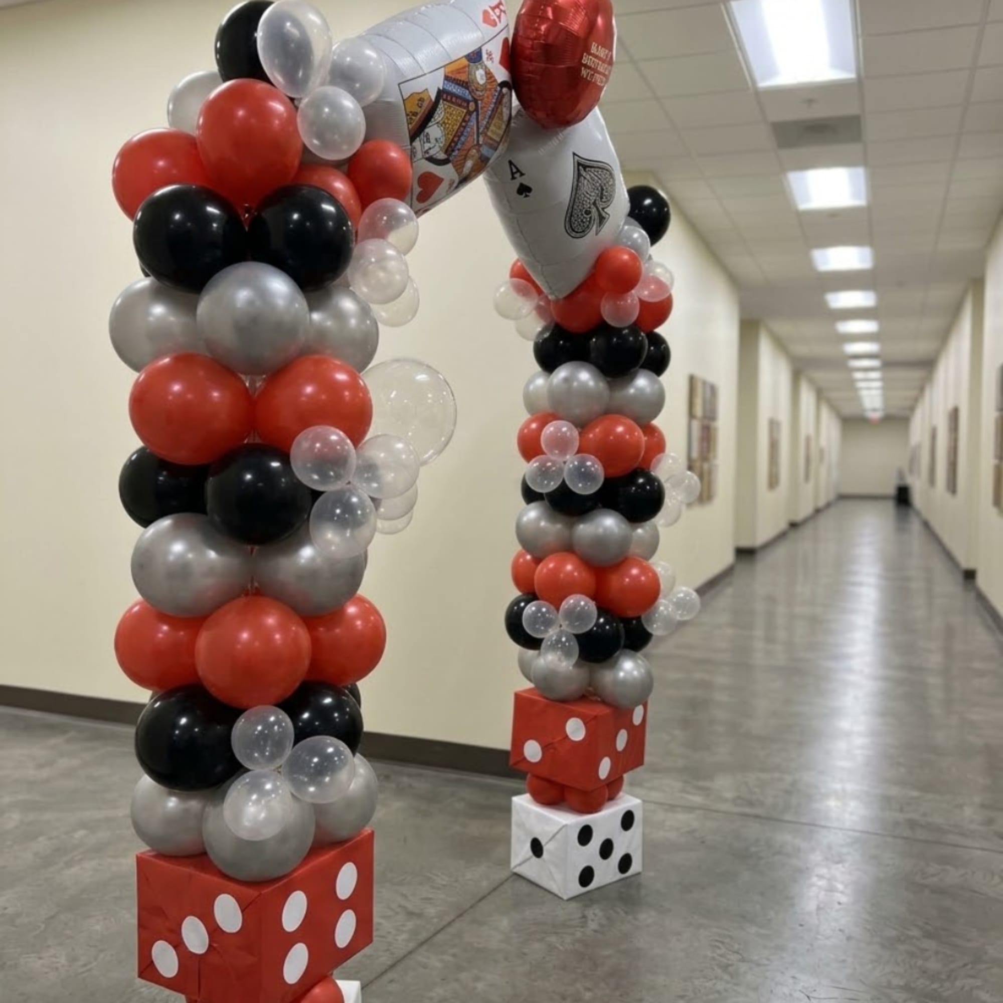 Balloon arch in red, black, silver, and clear balloons with dice bases