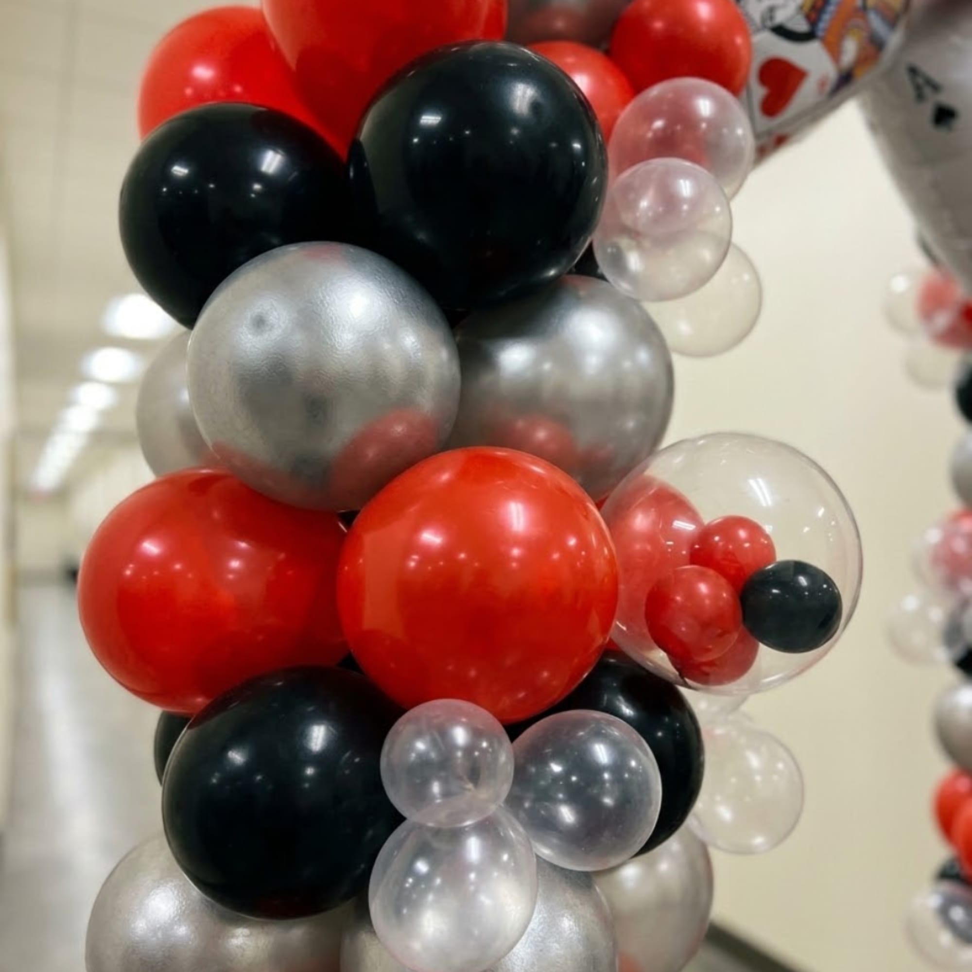Cluster of red, black, silver, and clear balloons arranged in a column