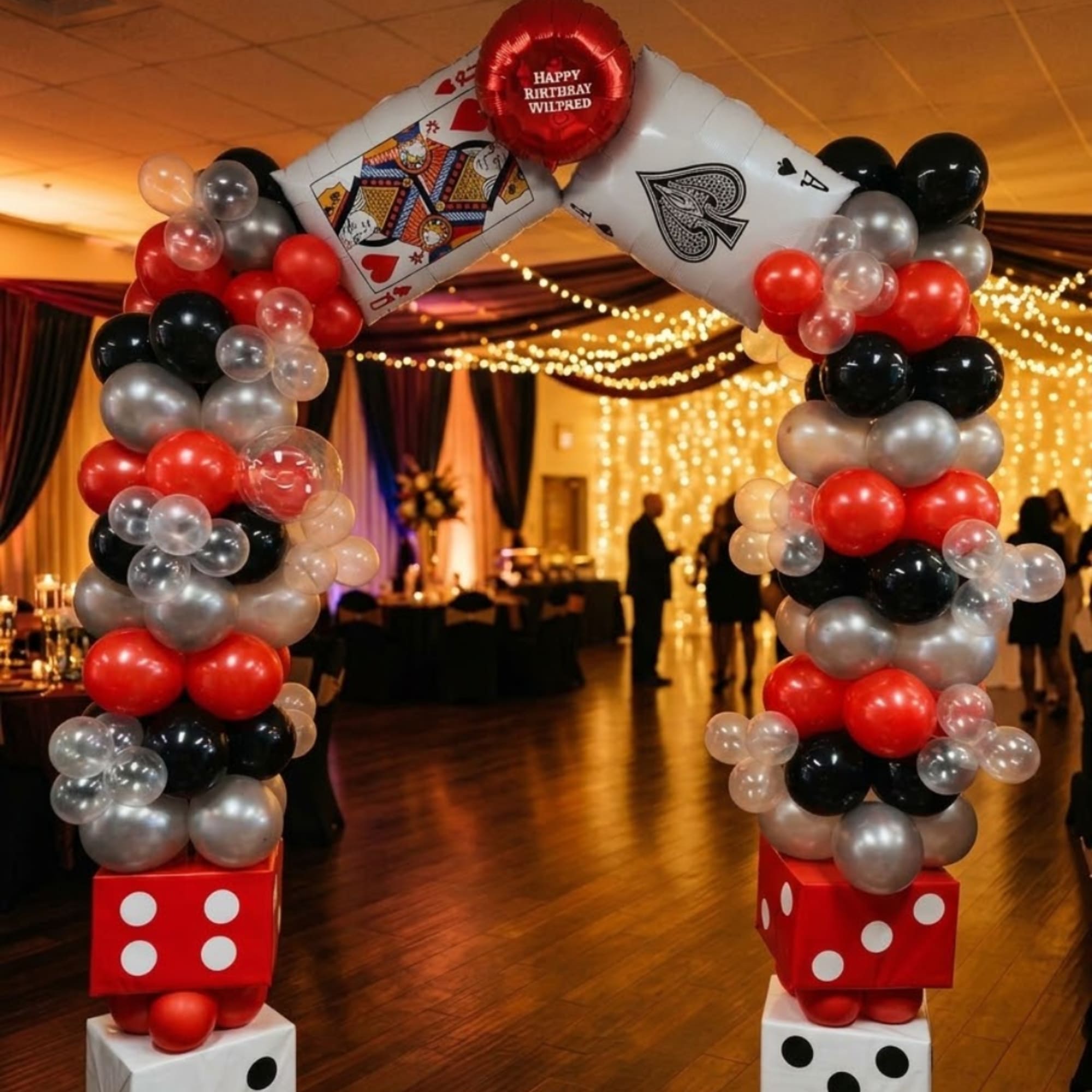 Balloon arch with playing-card and dice decorations at an indoor party