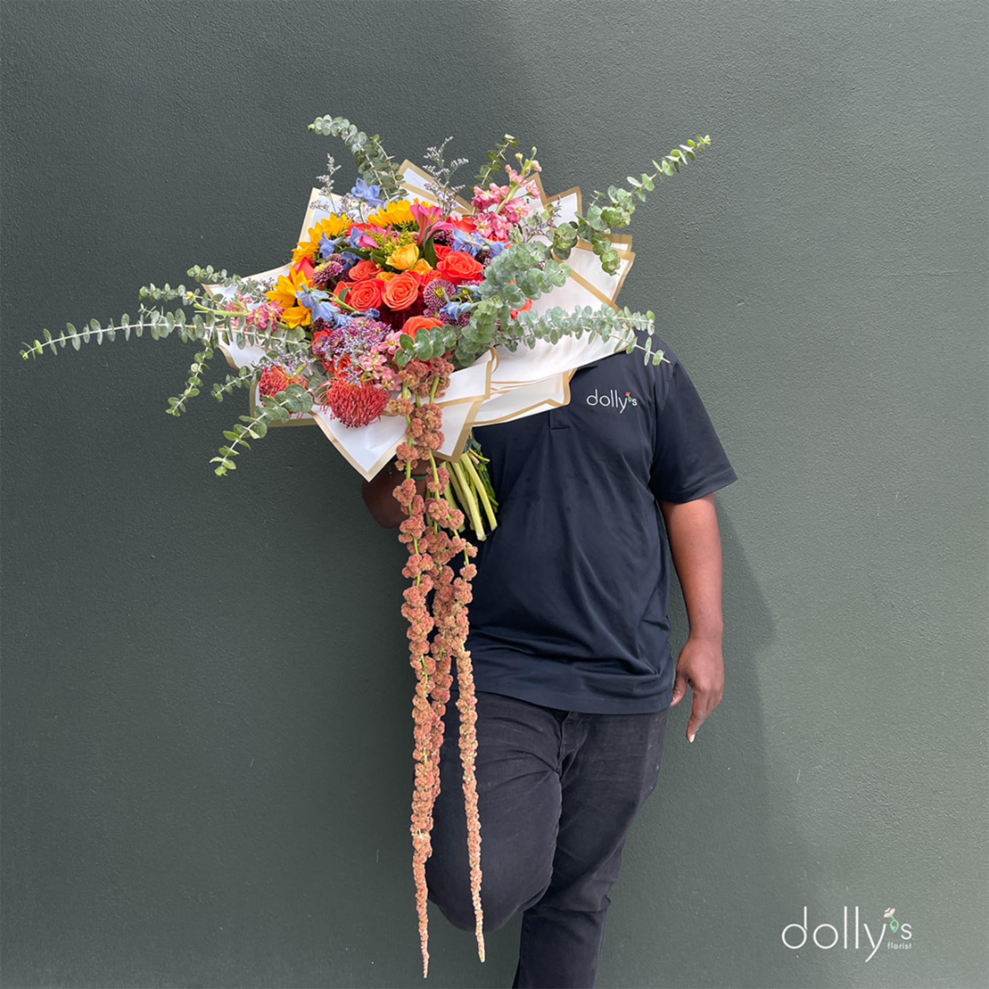 Large mixed bouquet with bright roses and sunflowers, wrapped in white paper