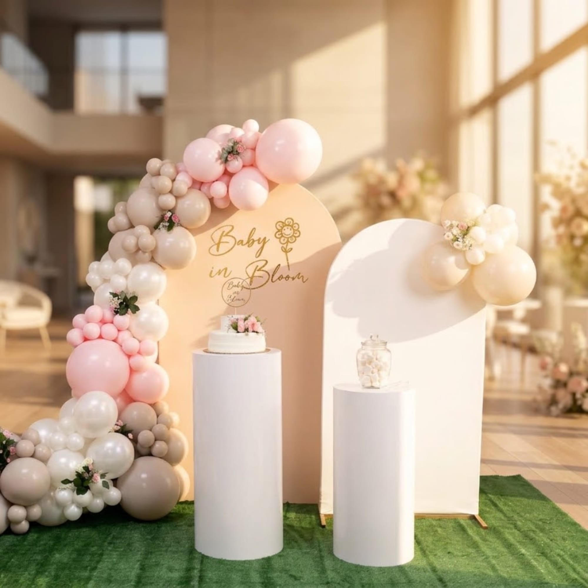 Pastel balloon arch around baby shower display boards with small floral accents