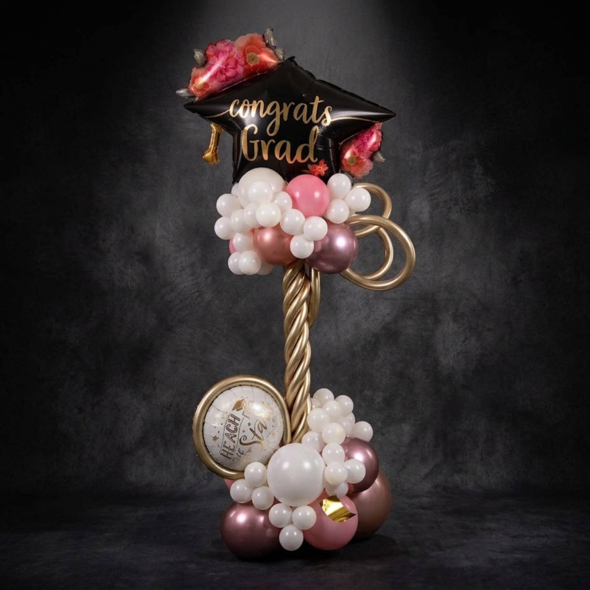 Graduation balloon display with a black star balloon and pink and white balloons