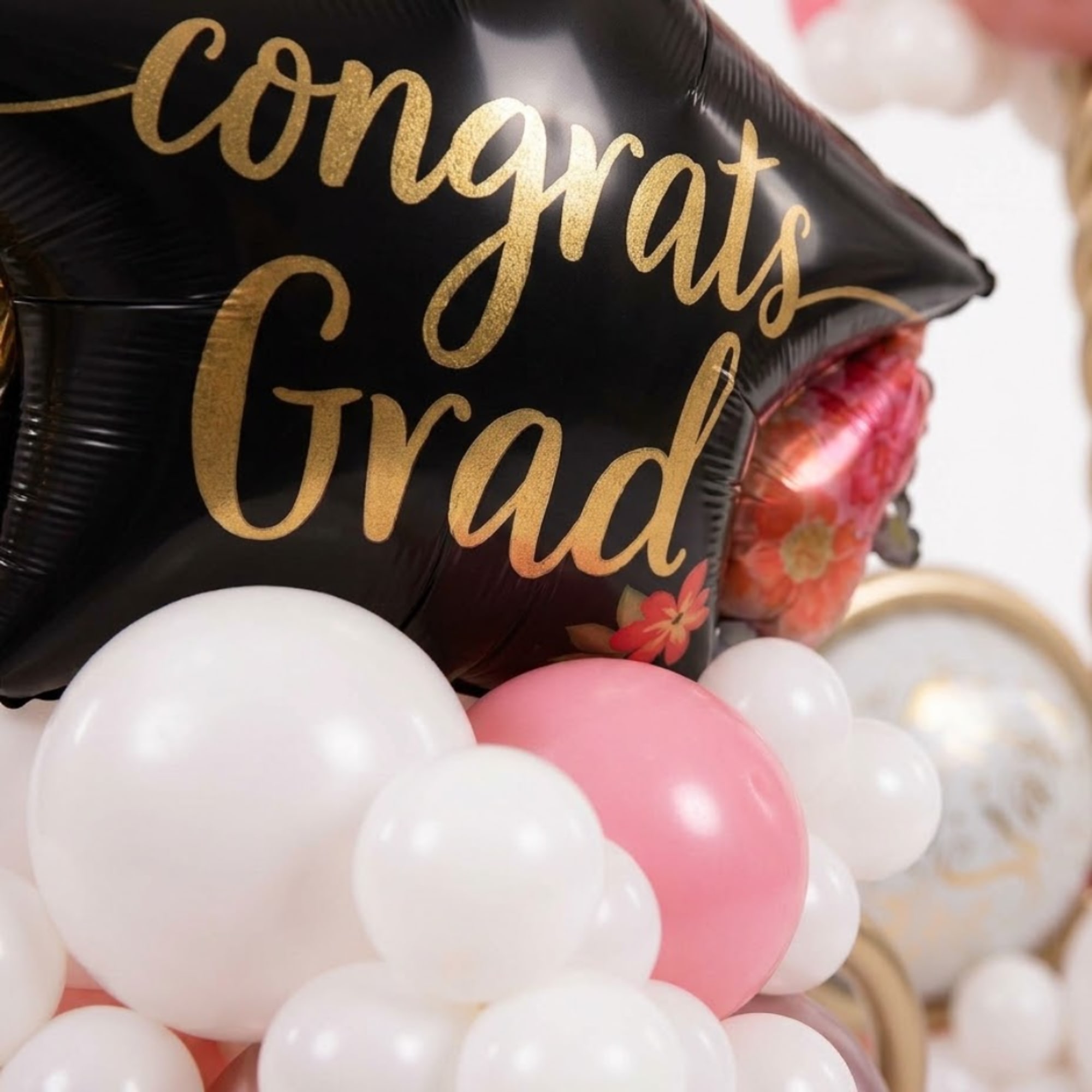 Black graduation balloon with gold lettering and pink and white balloons