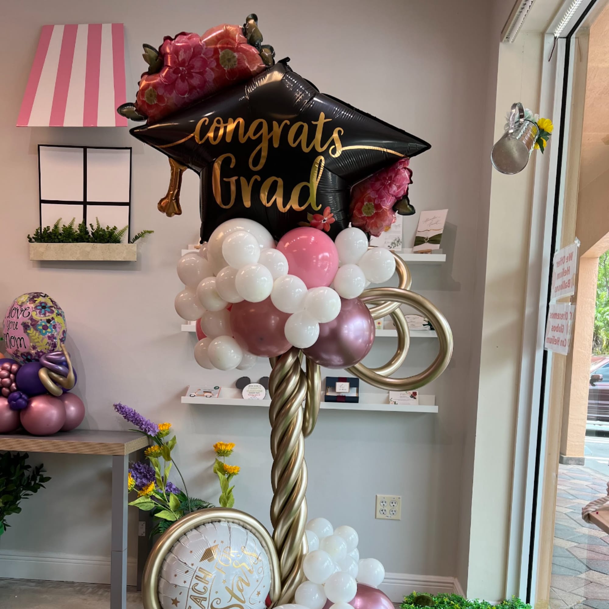 Graduation balloon display with a black cap balloon and pink floral accents
