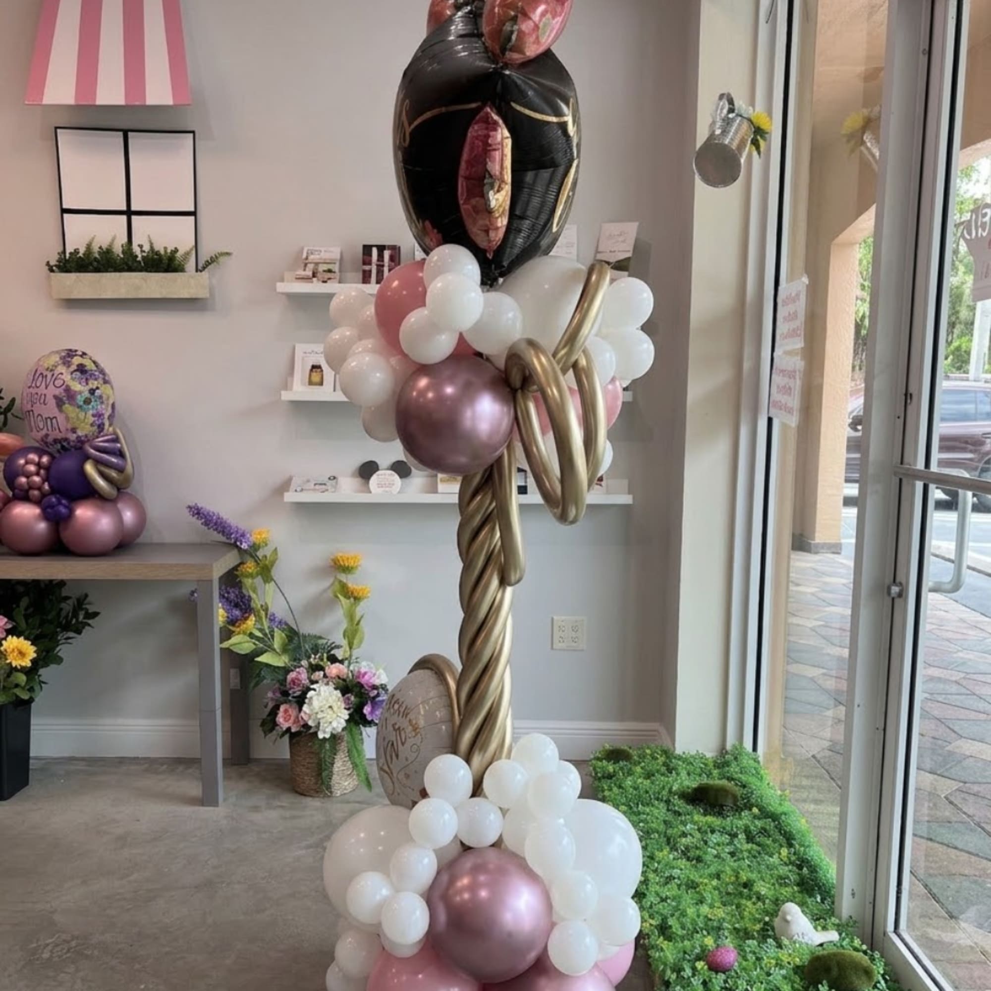 Balloon display with black, white, pink, and gold balloons in a shop interior.