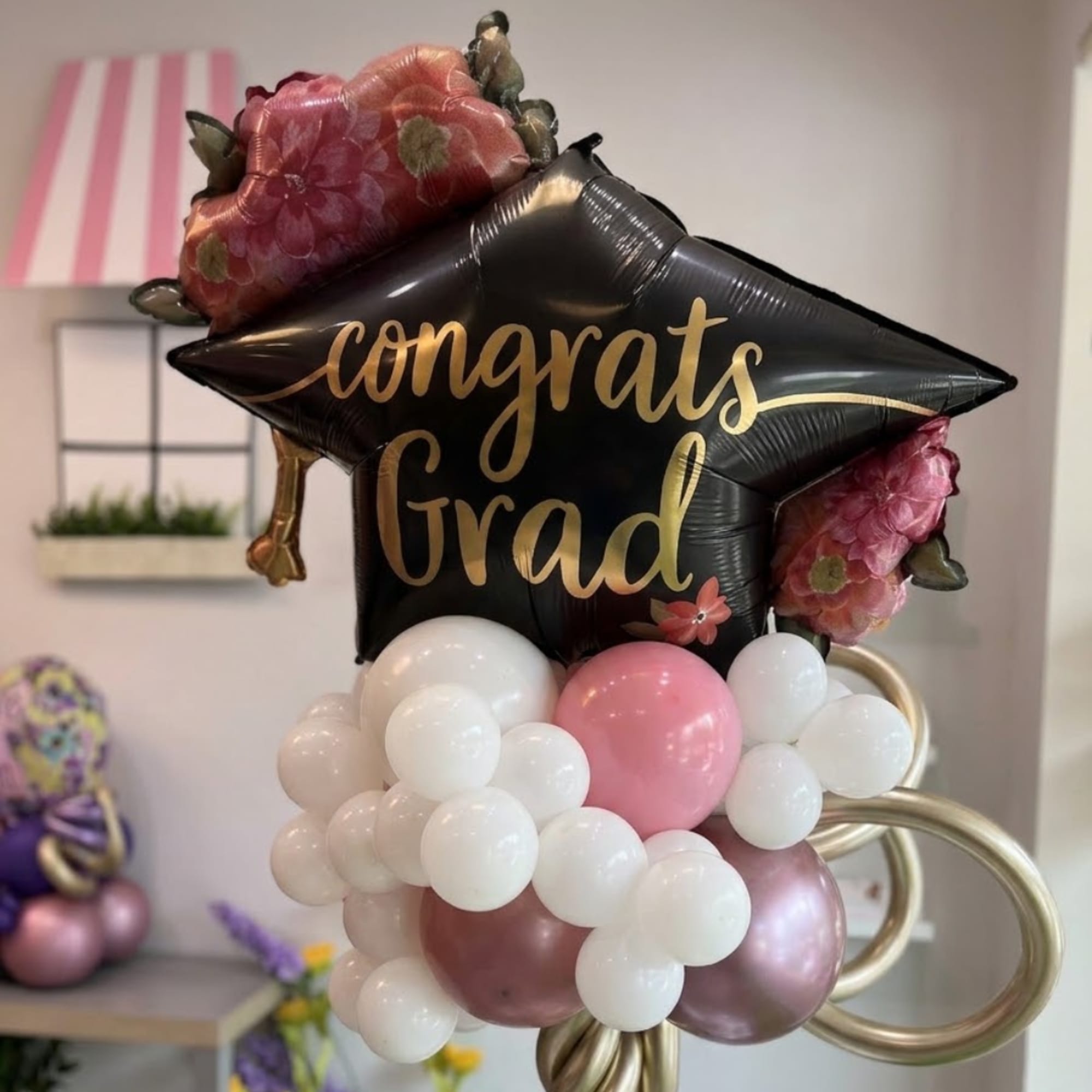 Graduation balloon arrangement with a black star balloon and pink floral accents