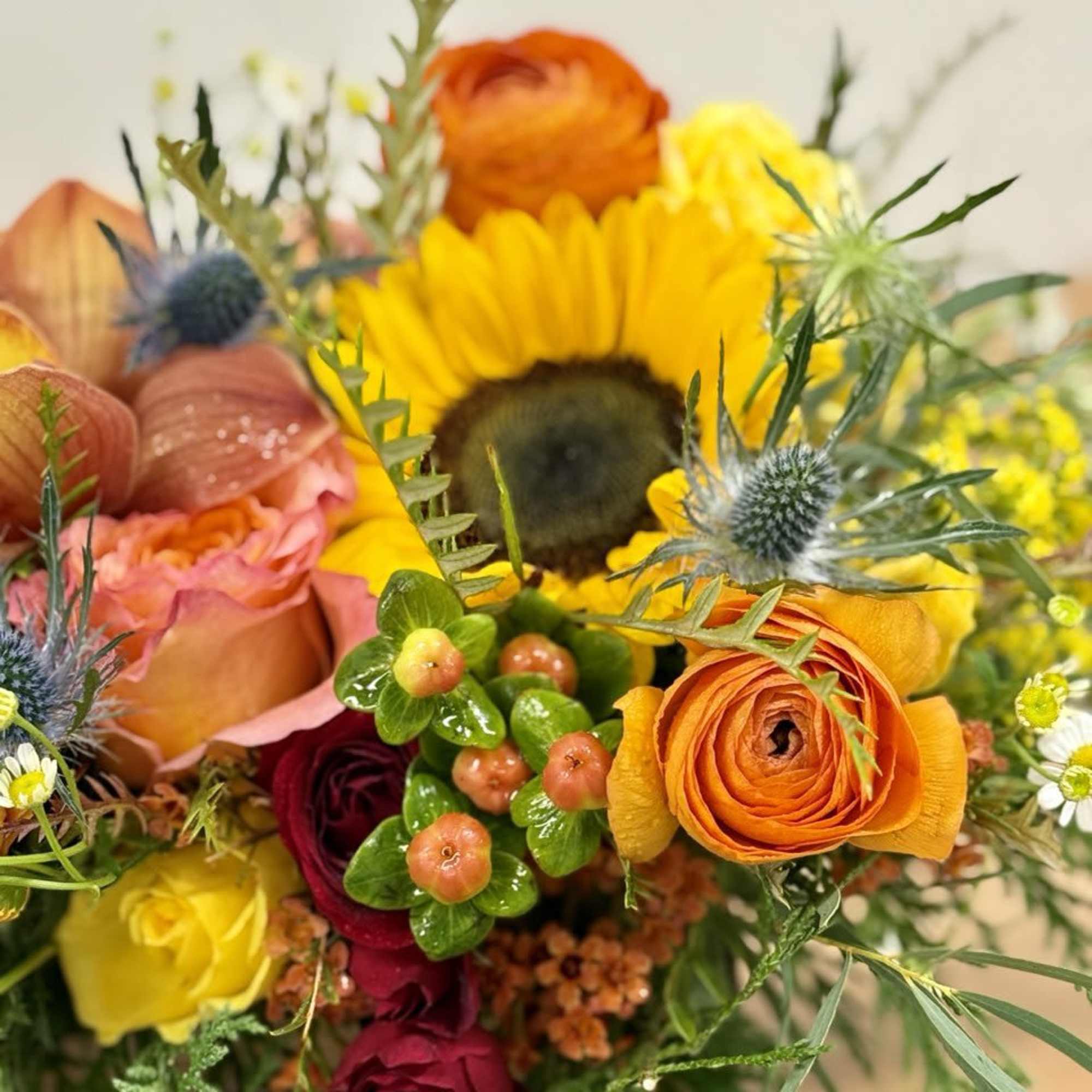 Mixed bouquet with sunflowers, orange ranunculus, and roses