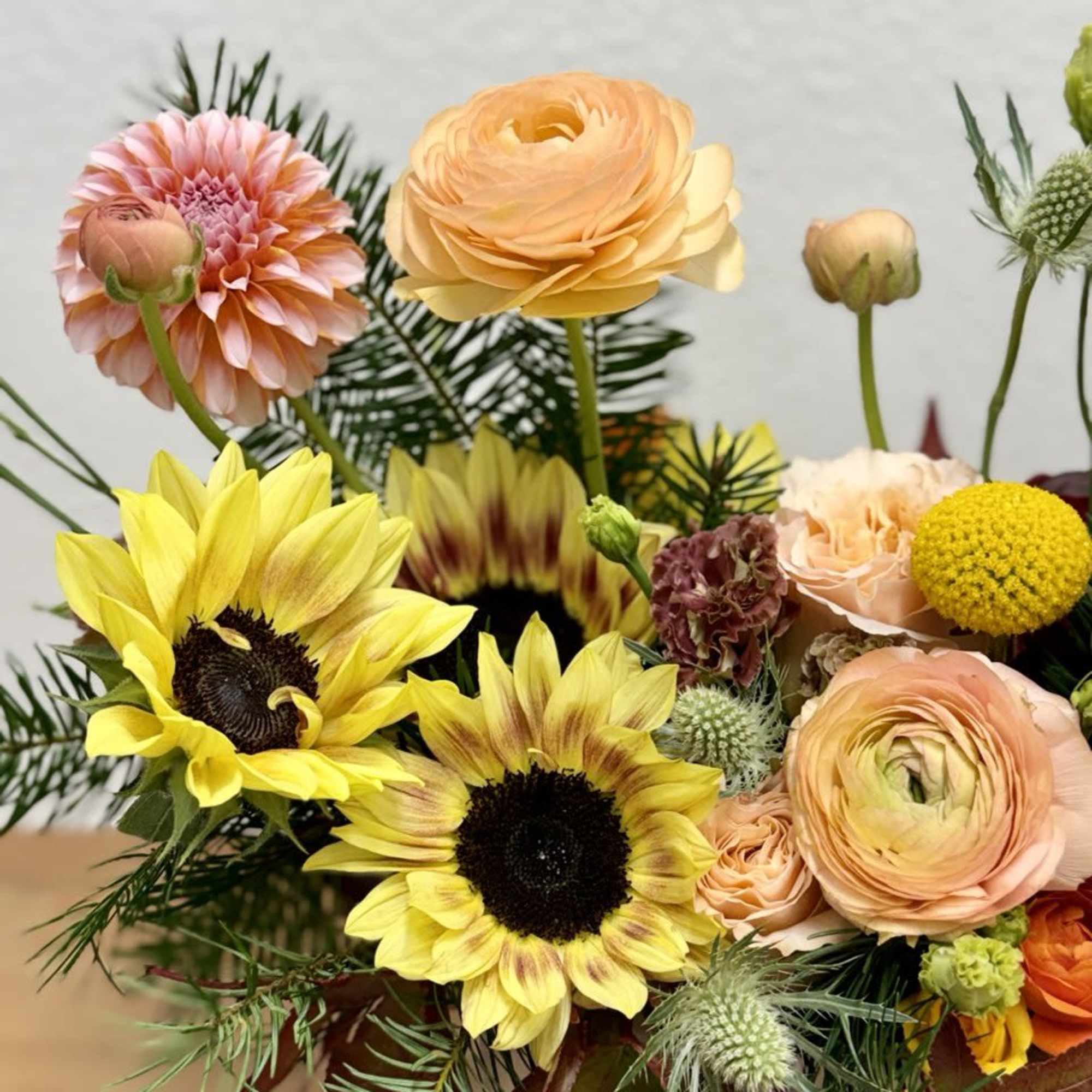Mixed bouquet with yellow sunflowers, peach ranunculus, and pink dahlias