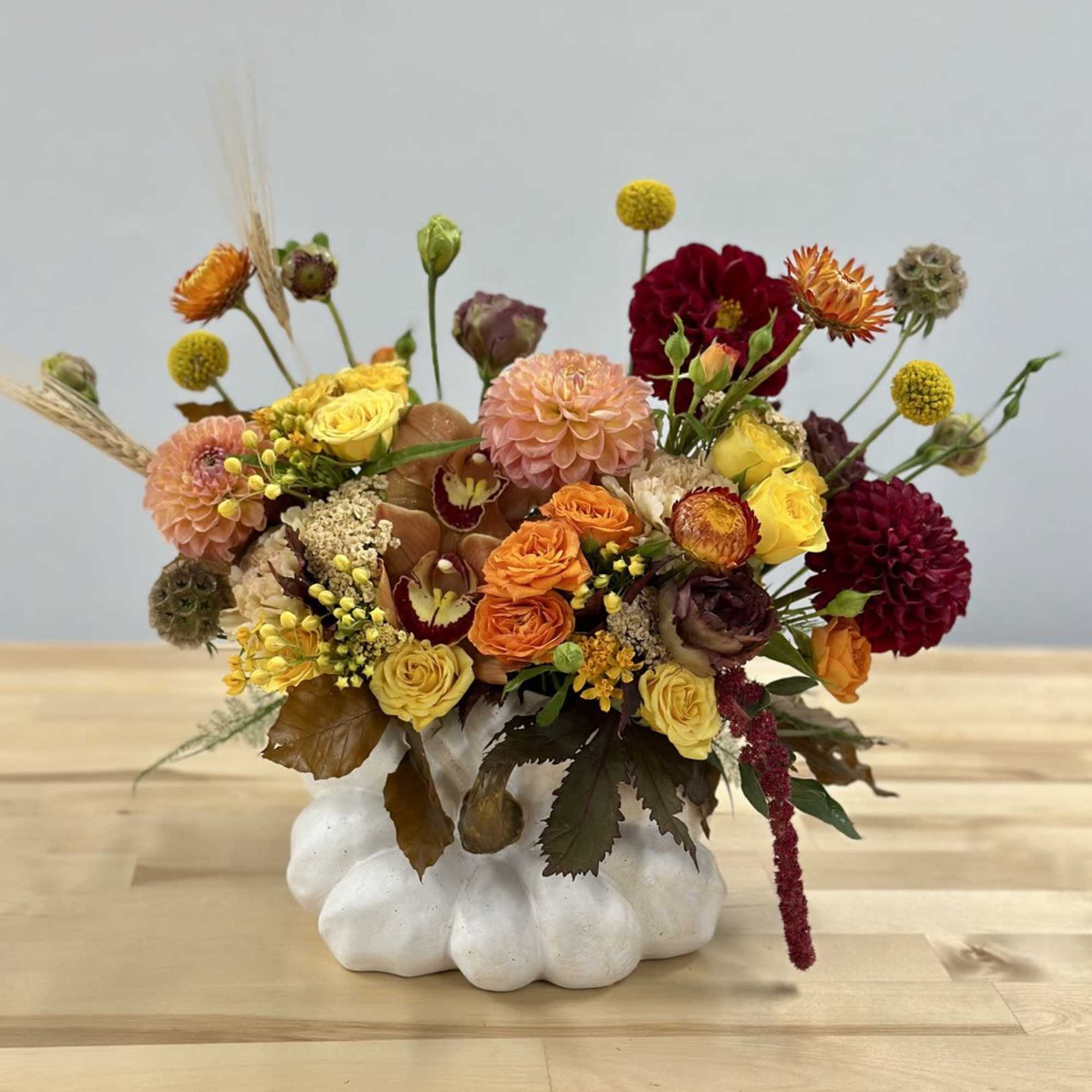 Mixed floral arrangement in a white pumpkin-shaped vase