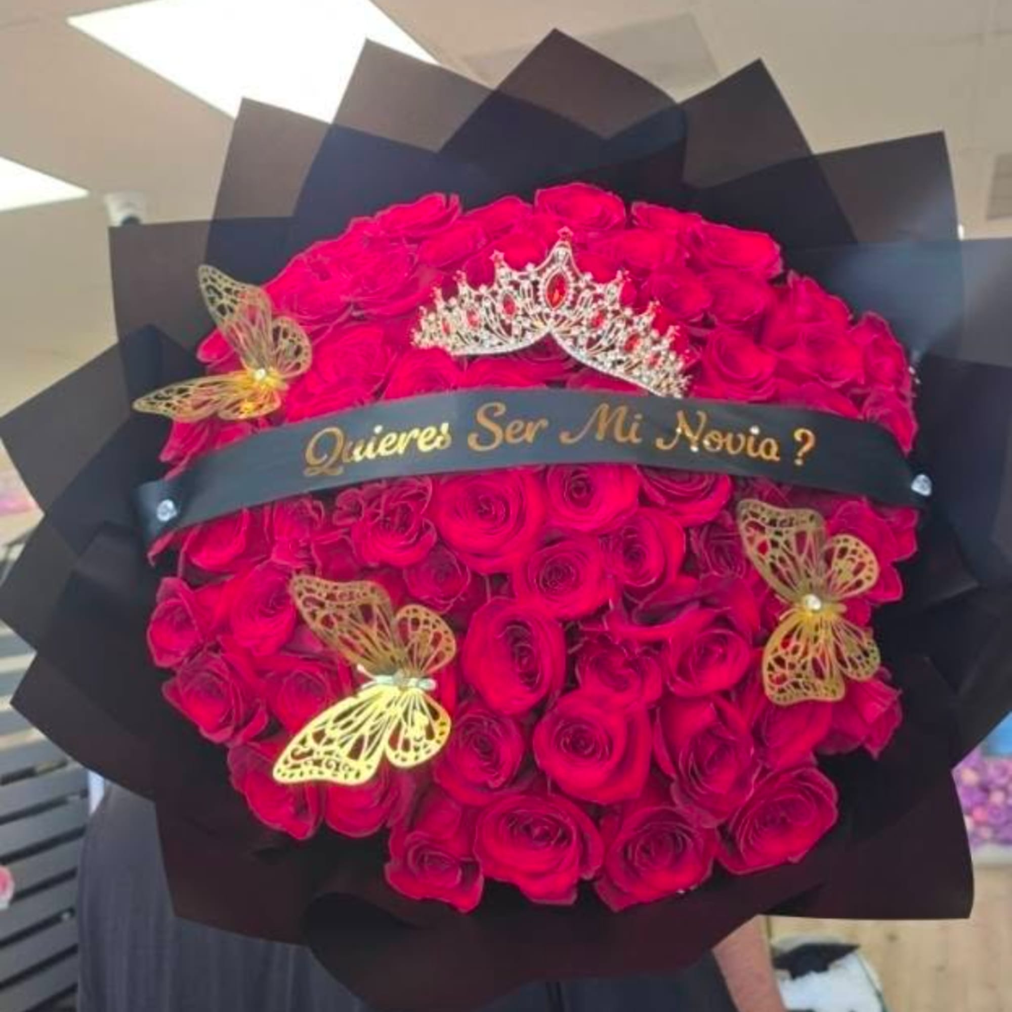 Round bouquet of red roses with a tiara and butterfly decorations