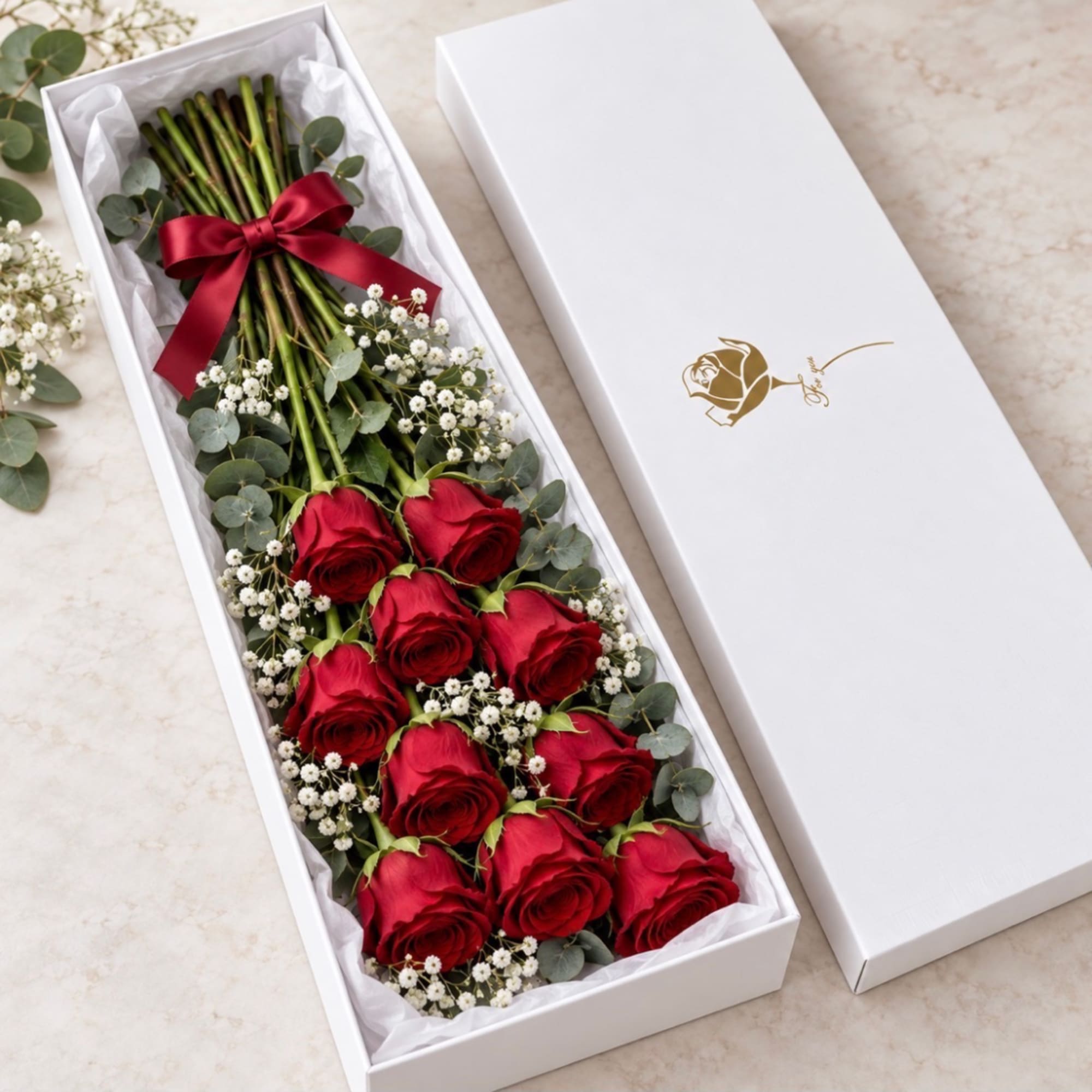 Red roses arranged in a white gift box with a red ribbon