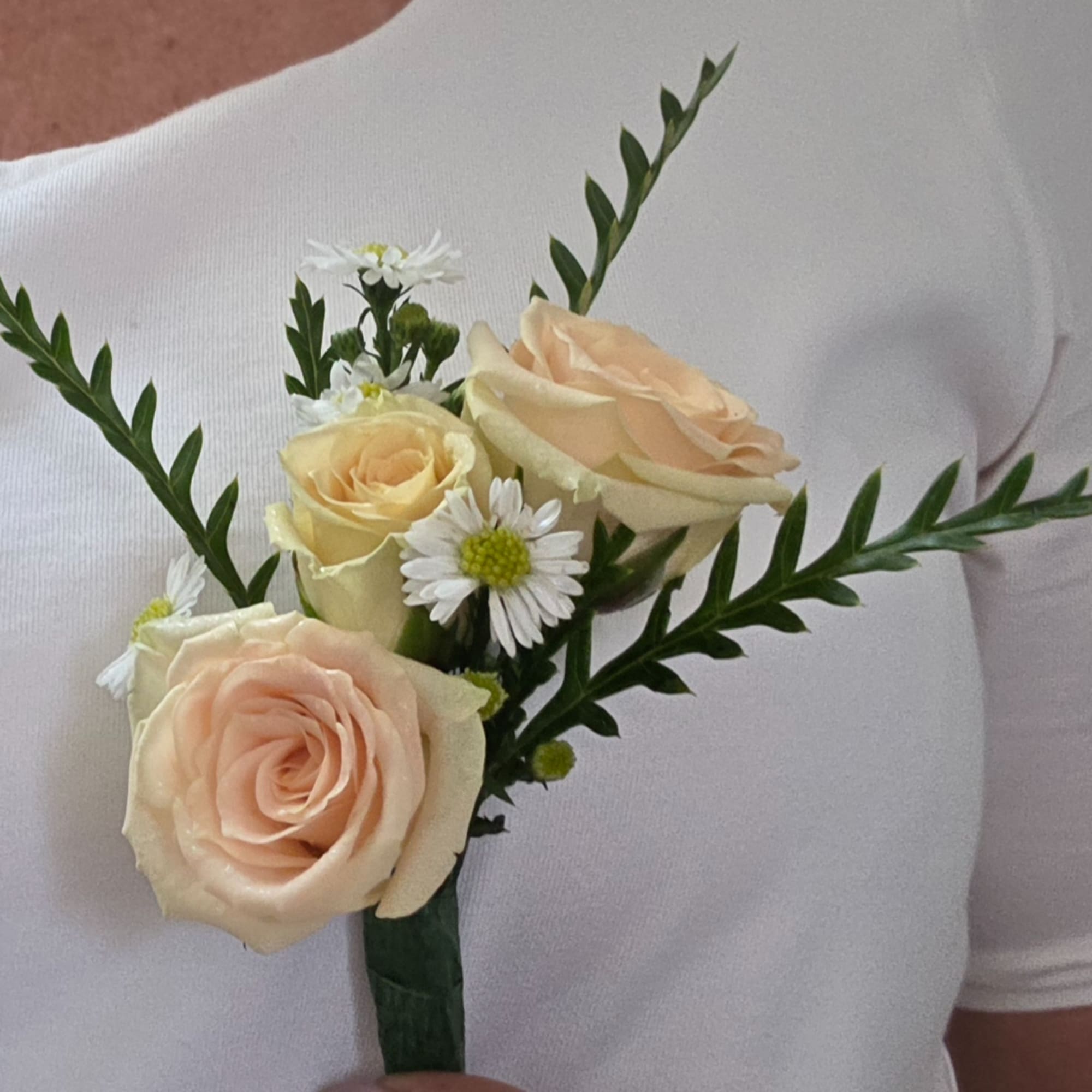 Small boutonniere with peach roses and white daisy flowers