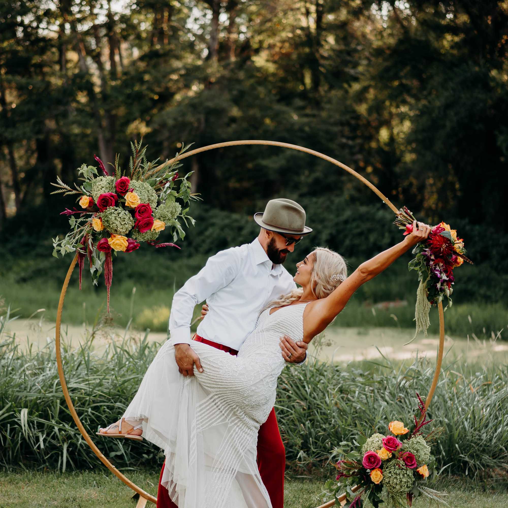 Couple posing in front of a floral hoop arch outdoors