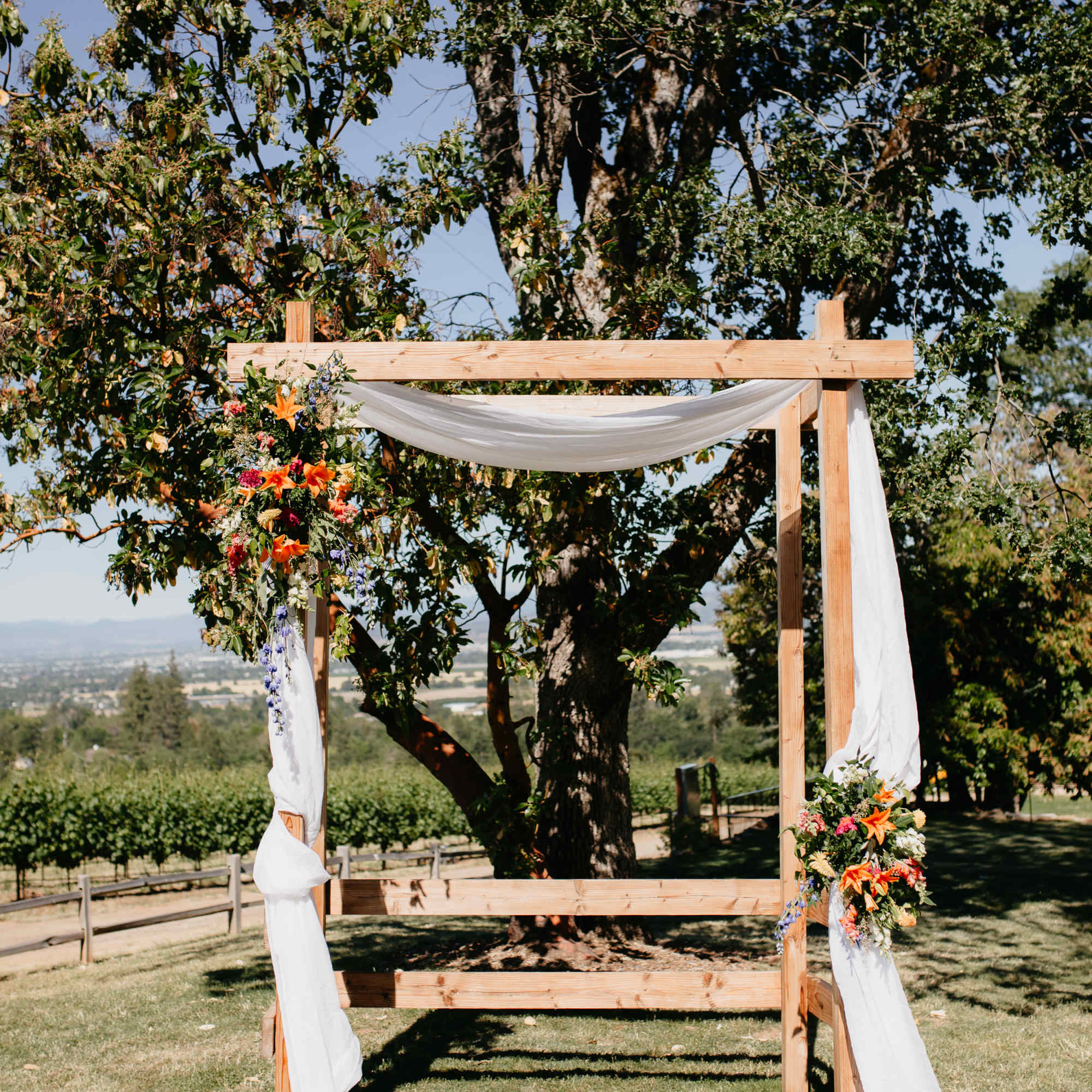 Wooden wedding arch with white draping and floral clusters