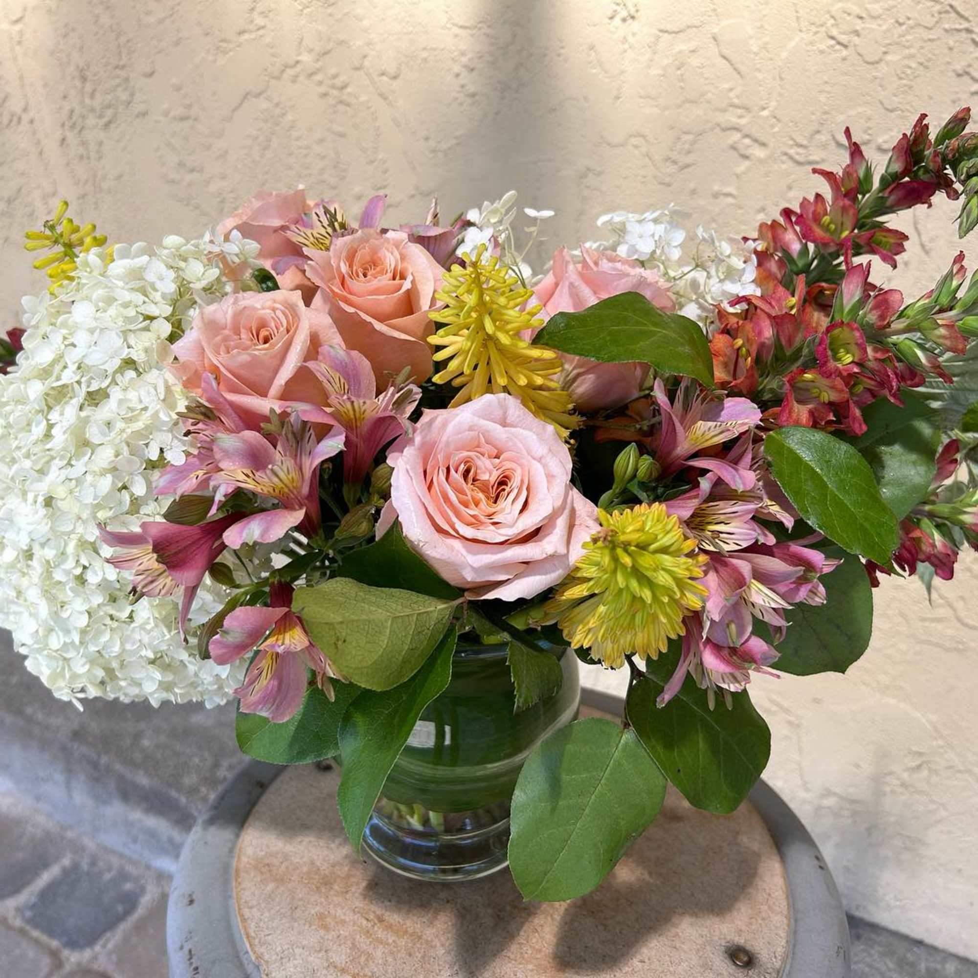 Pink roses and mixed blooms arranged in a glass vase