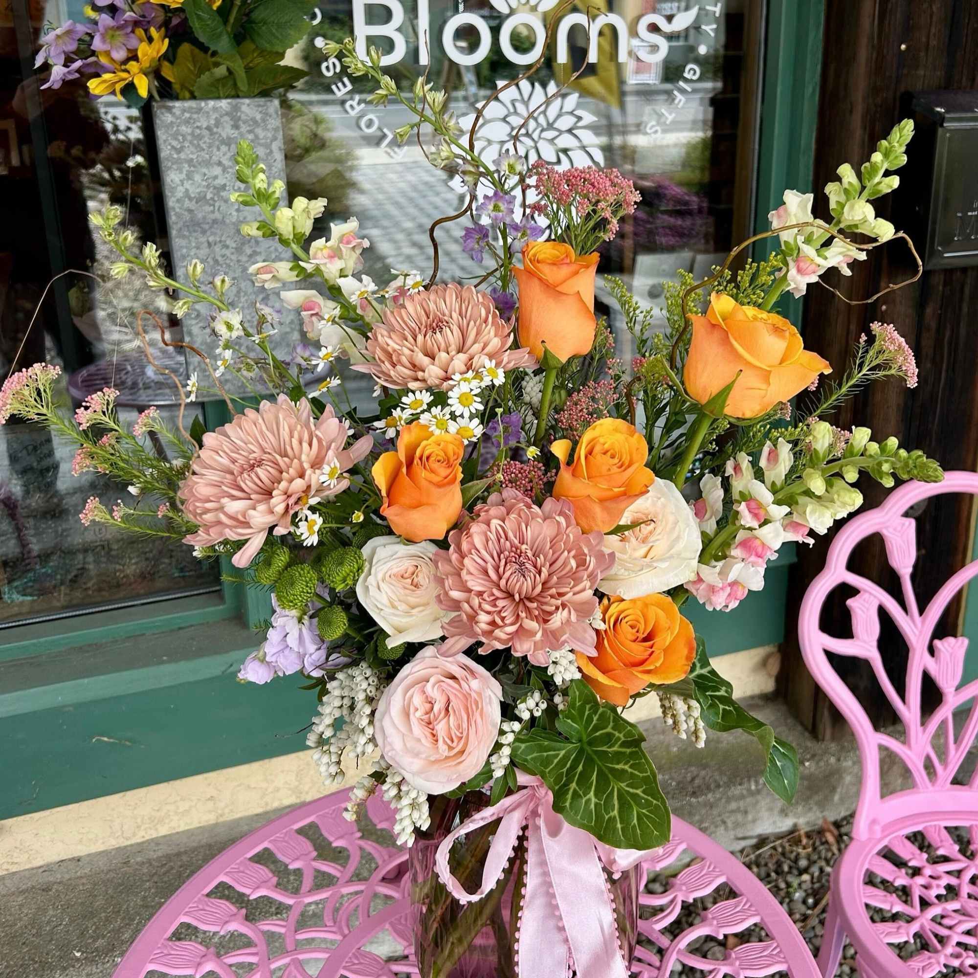 Mixed bouquet of orange roses and blush chrysanthemums in a glass vase
