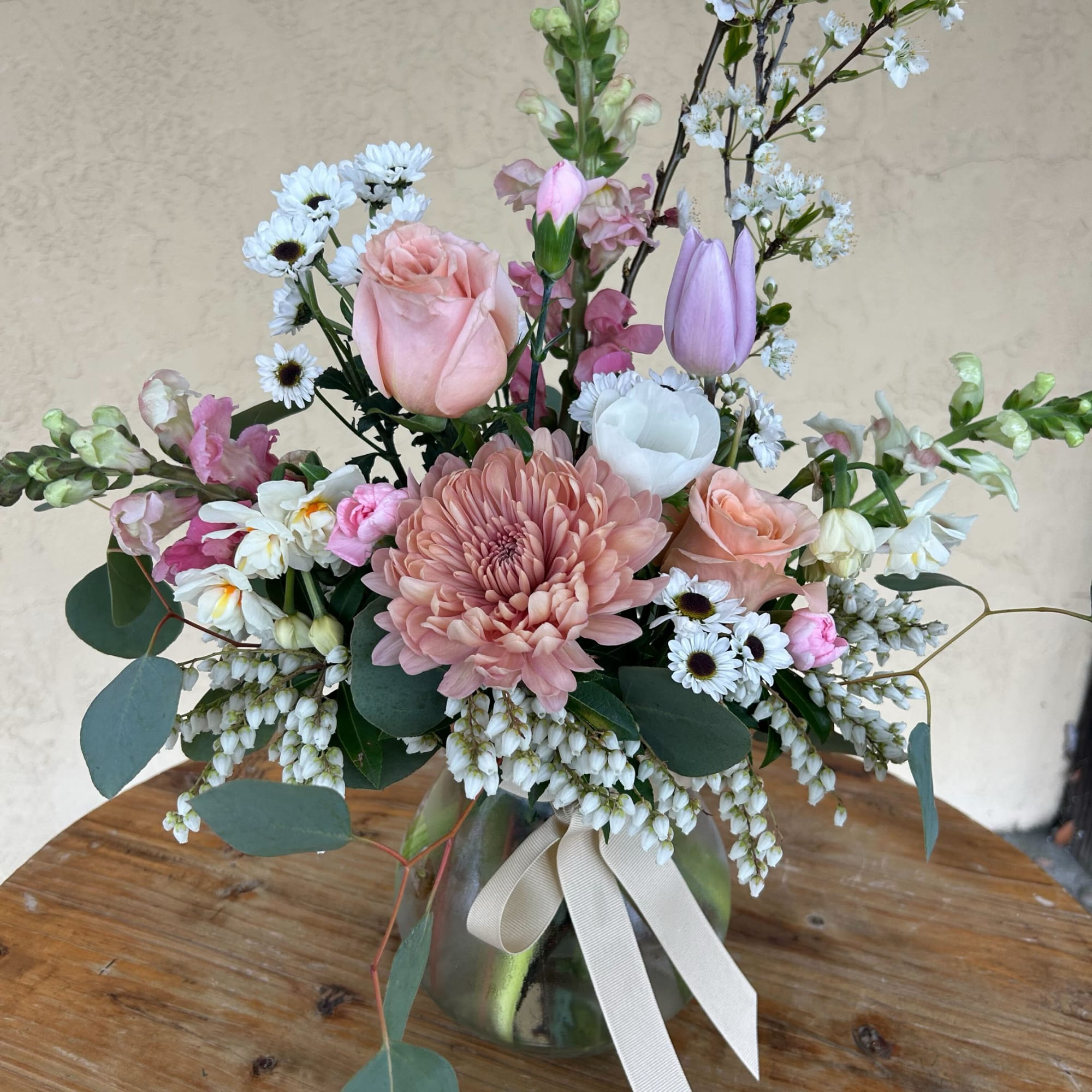 Pastel bouquet in a glass vase with roses, daisies, and tulips