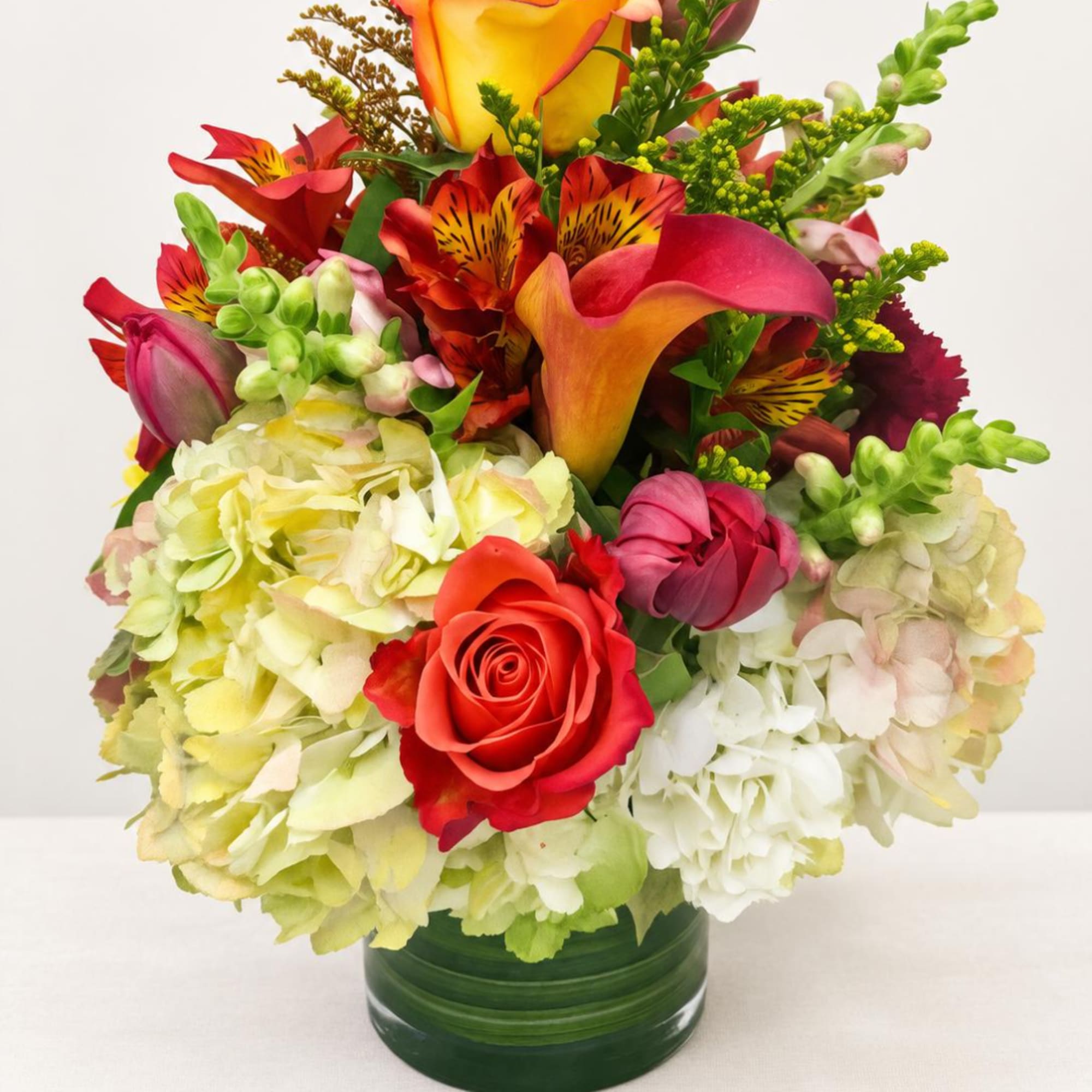Colorful bouquet with roses, calla lilies, hydrangeas, and alstroemeria in a glass vase