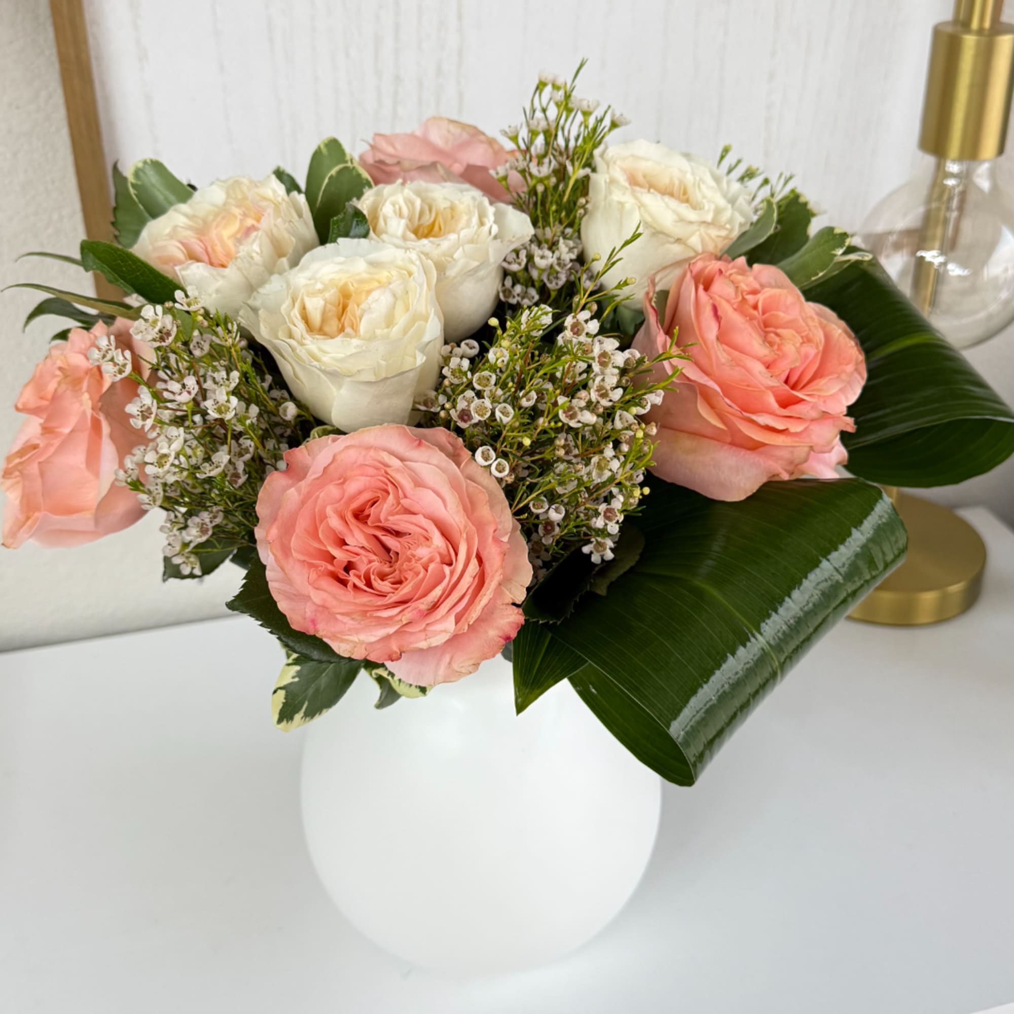 Pink and white roses arranged in a white vase