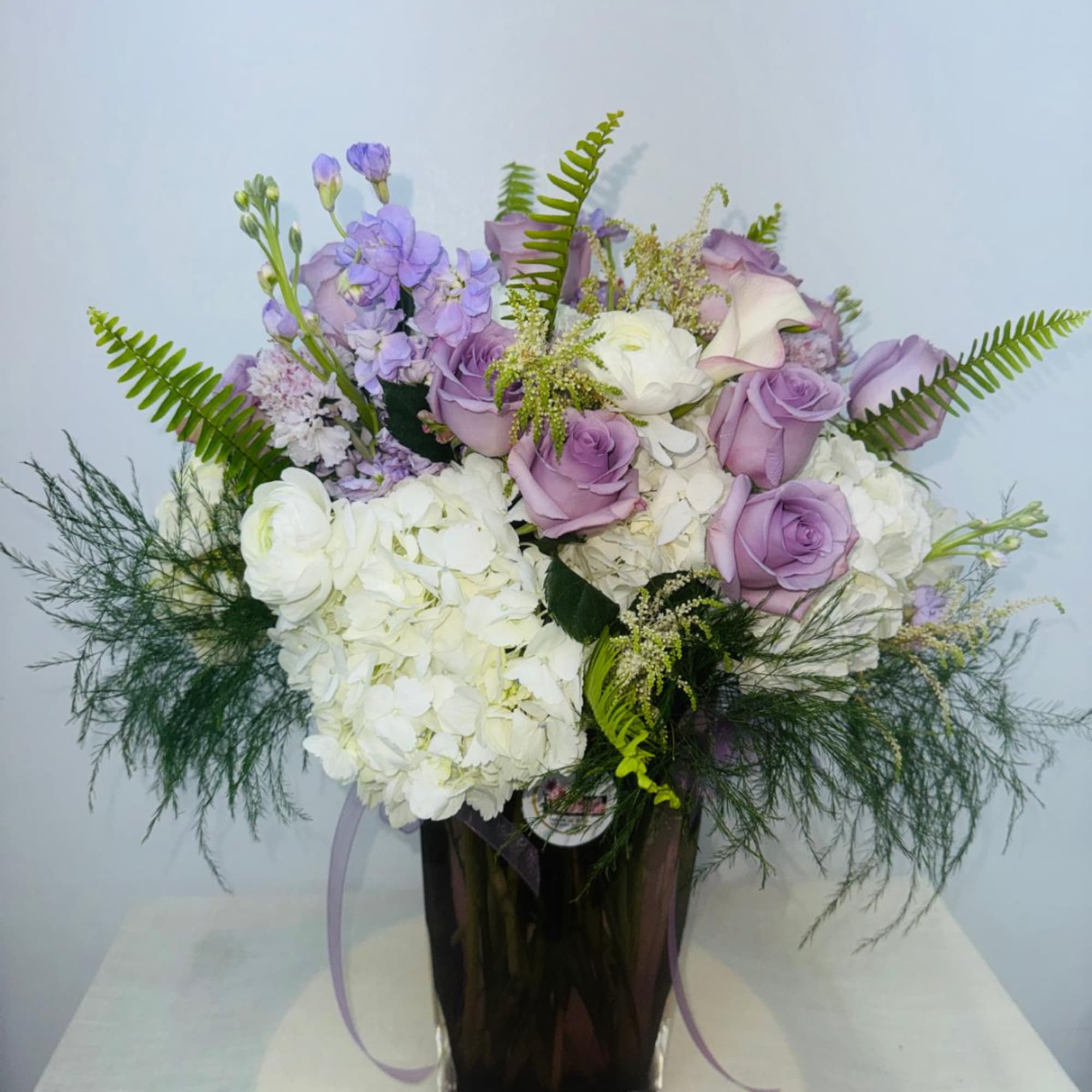 Lavender roses and white hydrangeas in a tall vase with fern accents, photo 4 of 4