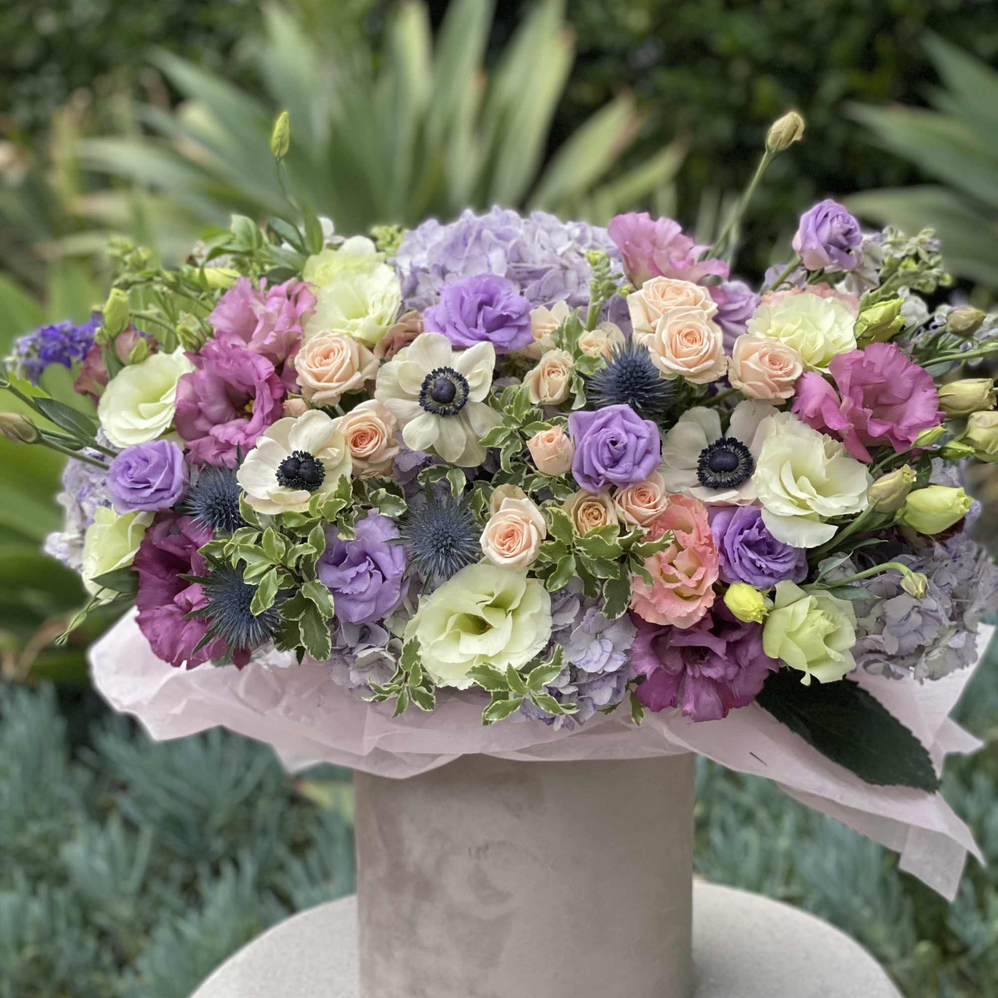 Pastel bouquet of roses, lisianthus, hydrangeas, and anemones in a hatbox