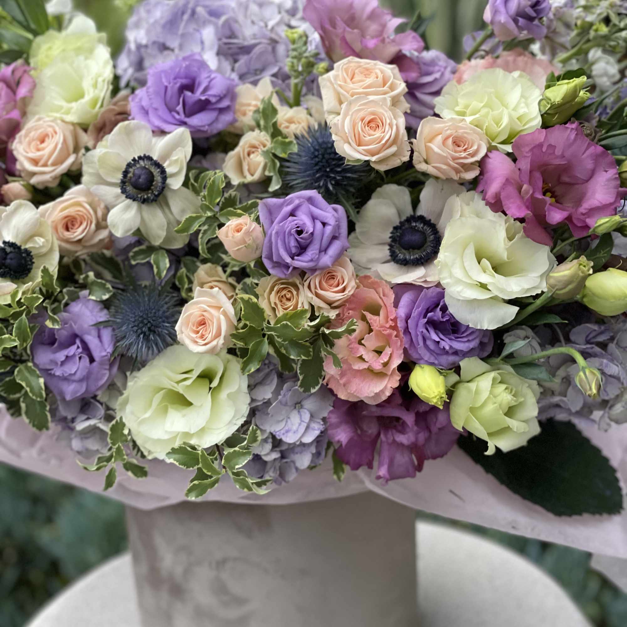 Pastel bouquet of roses, lisianthus, hydrangea, and anemones in a vase