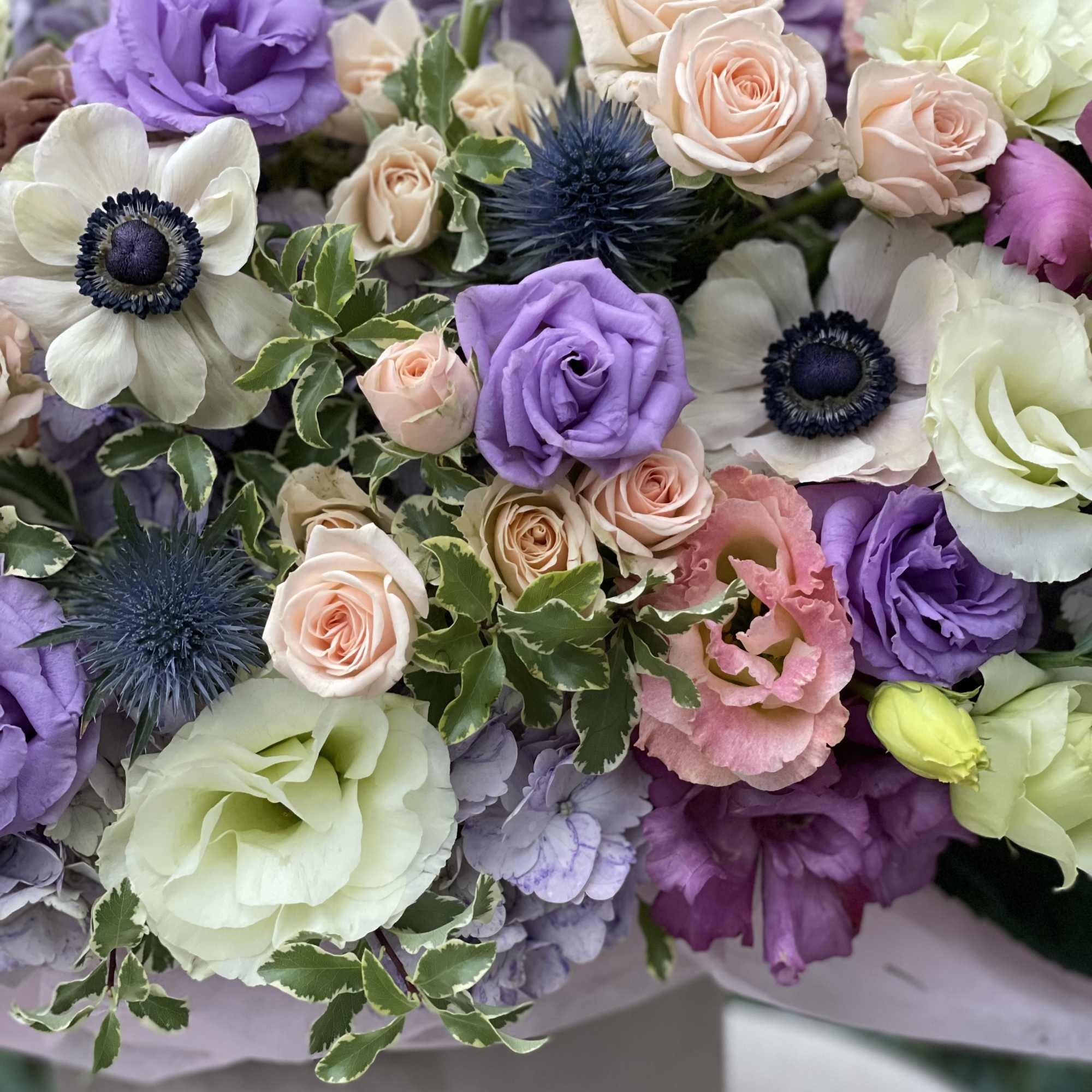 Bouquet of pastel roses, lisianthus, and anemones in lavender and cream