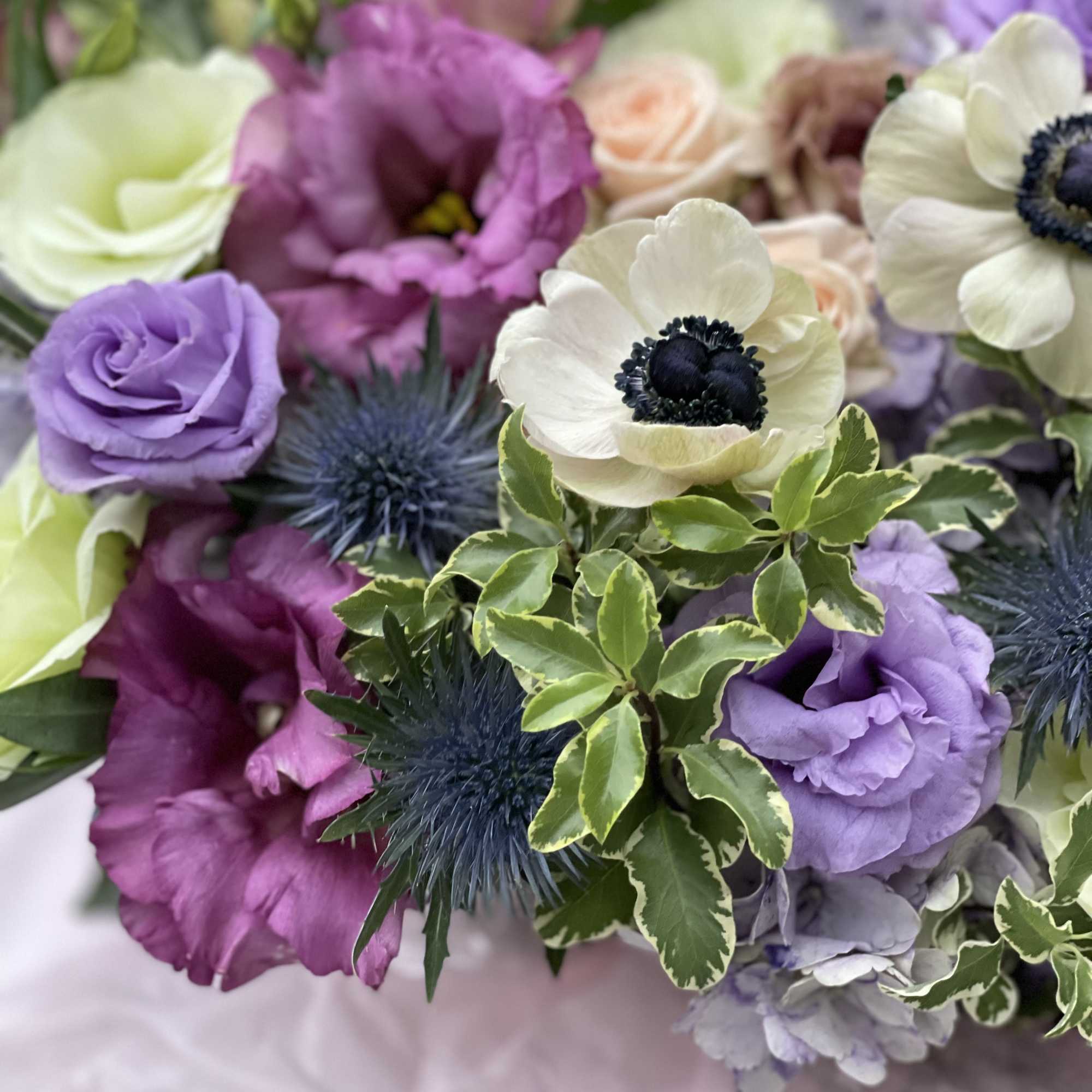 Bouquet of purple, white, and peach flowers with spiky blue accents