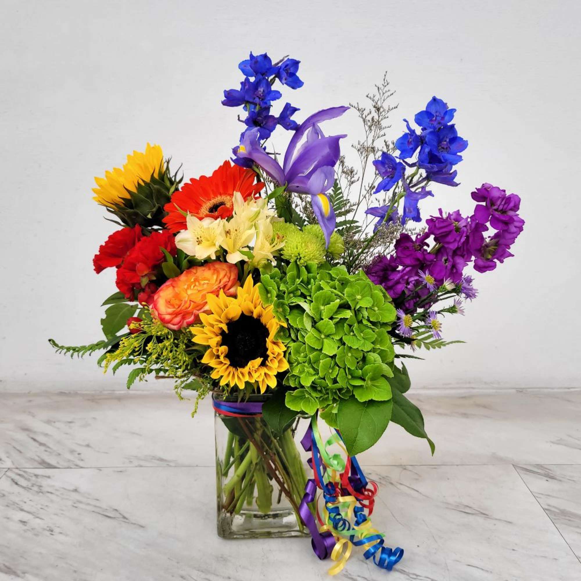 Colorful mixed bouquet in a clear glass vase with ribbon curls