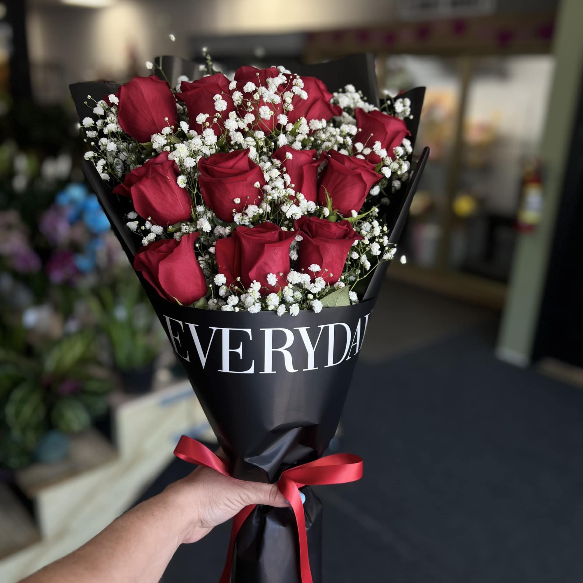 Bouquet of red roses with white baby's breath in black wrapping