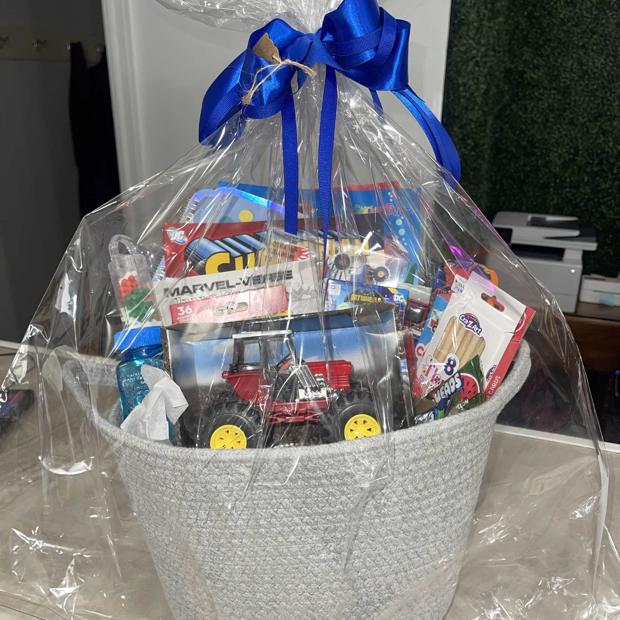 Gift basket with toys and candy wrapped in clear plastic and tied with a blue ribbon