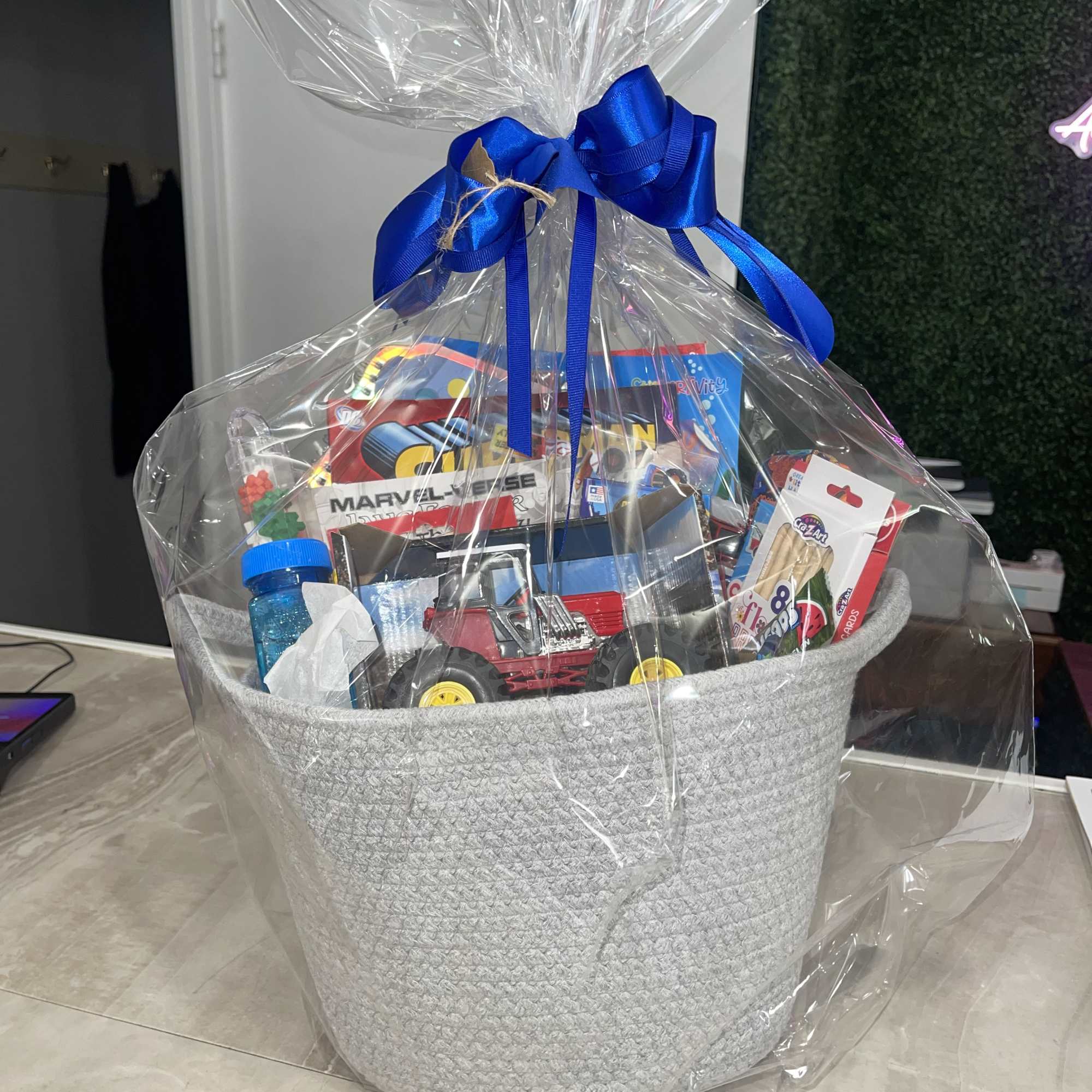 Gift basket wrapped in clear cellophane with a blue ribbon