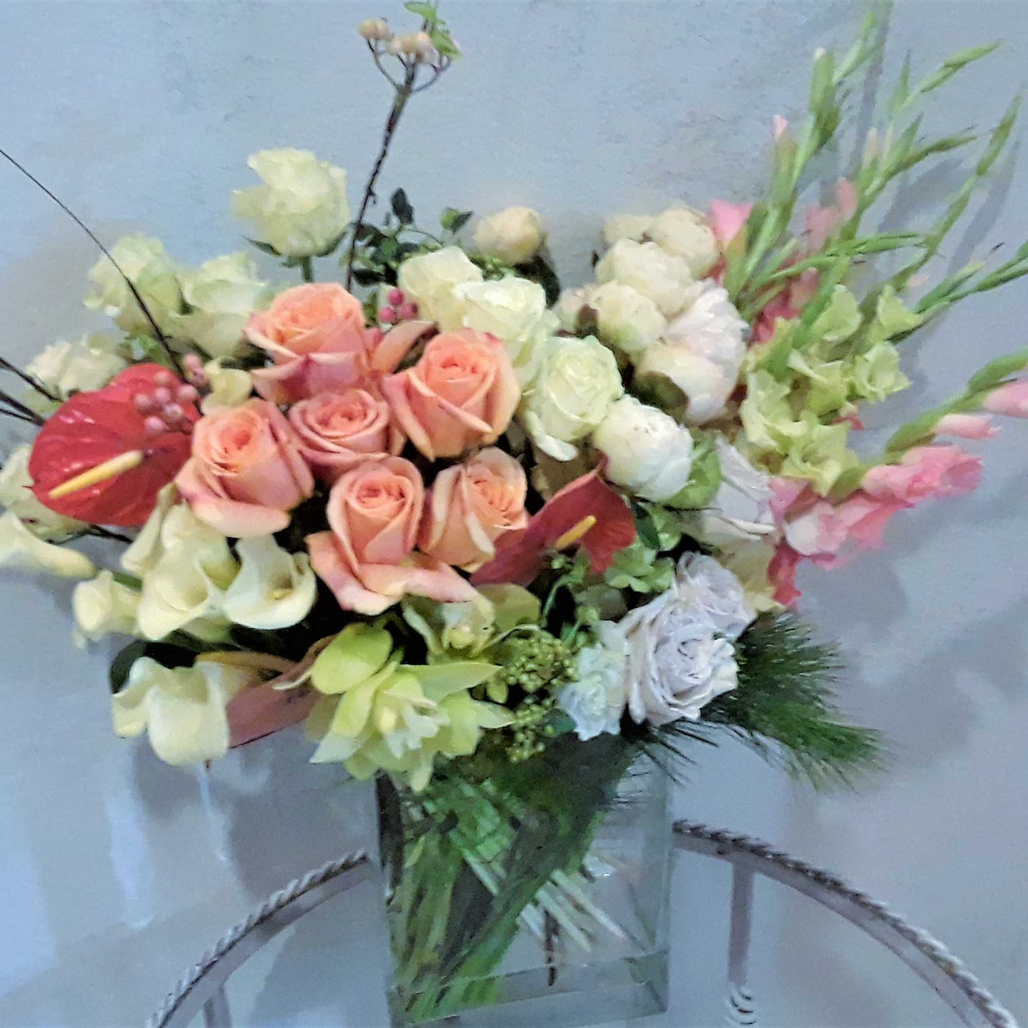 Mixed bouquet of pink roses, white calla lilies, and pale blooms in a glass vase