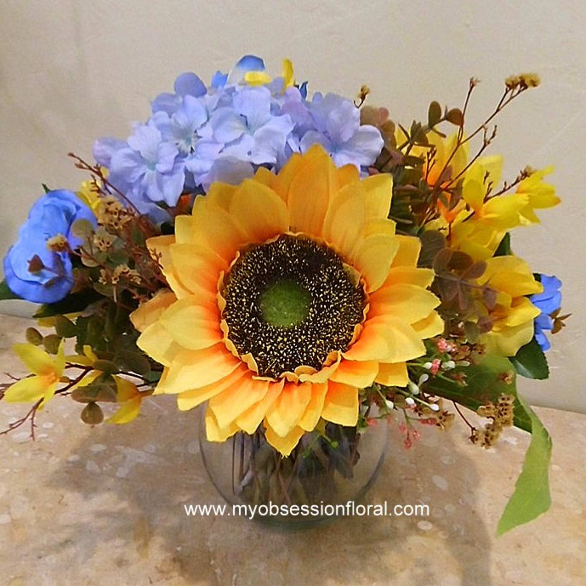 Sunflower bouquet with blue and yellow flowers in a glass vase