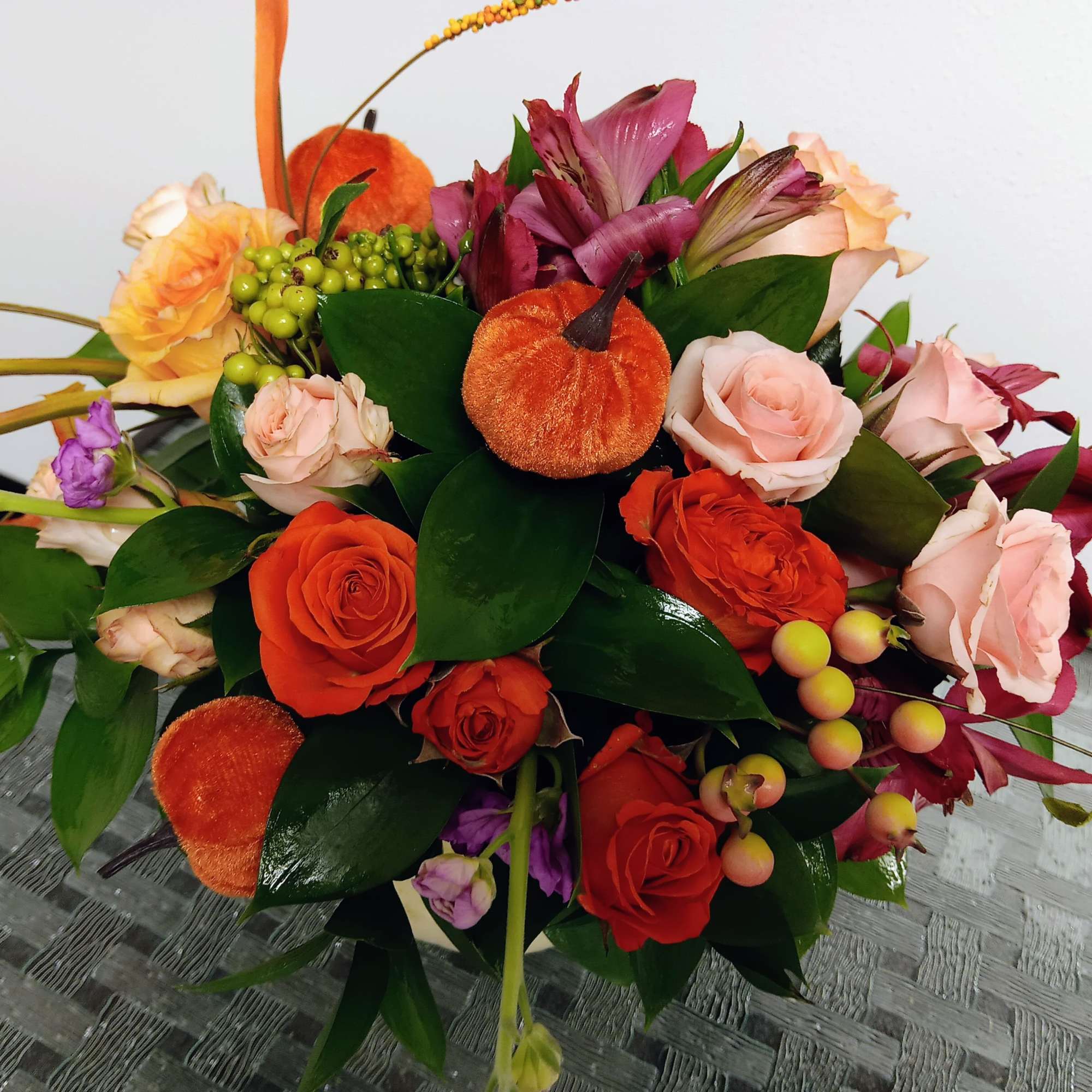 Bouquet of orange and pink roses with purple blooms and berries