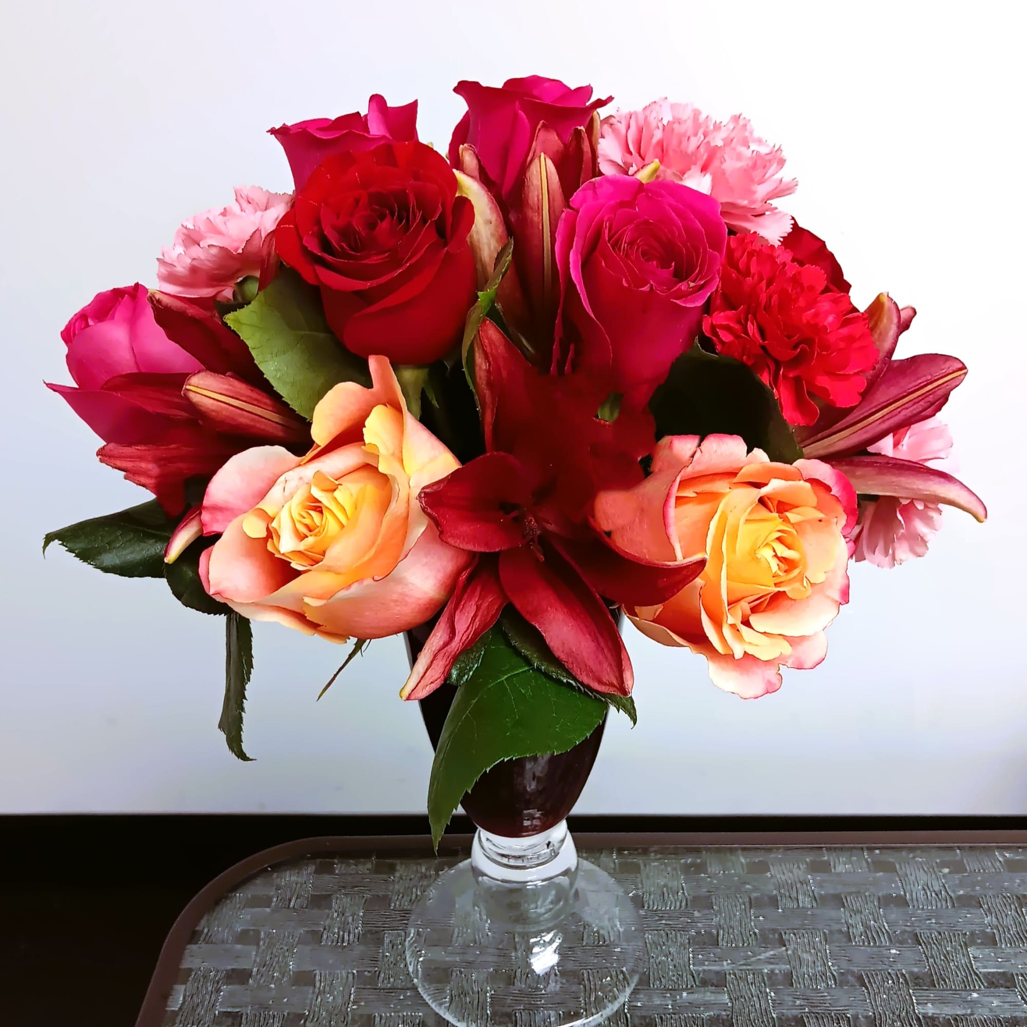 Bouquet of red and pink roses with lilies in a glass vase