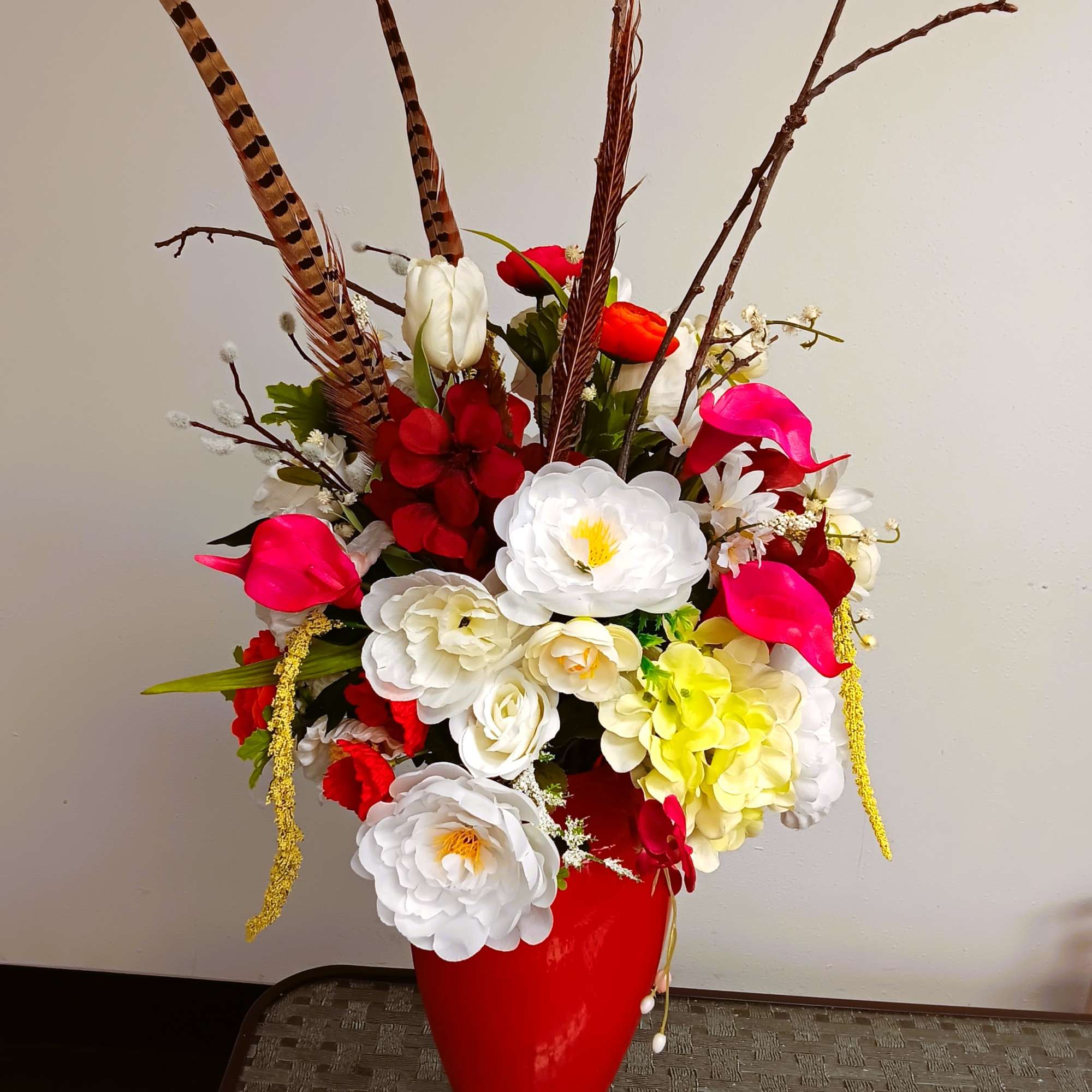 Tall floral arrangement in a red vase with white, red, pink, and yellow blooms
